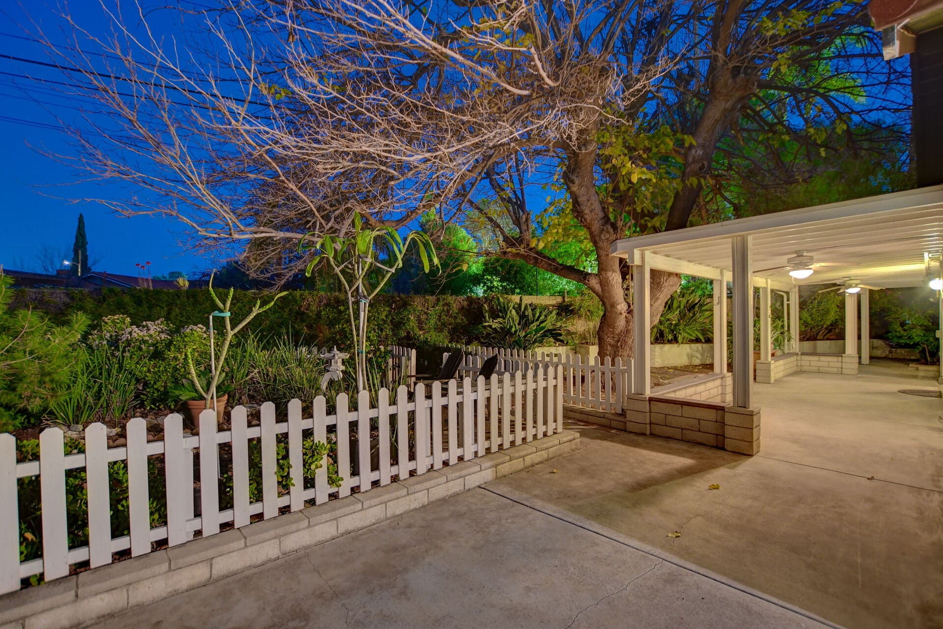 Claremont garden patio at dusk behind a white picket fence