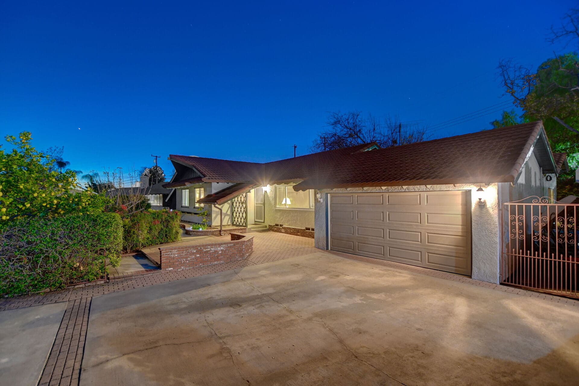 Spanish-tile Claremont home at twilight with wrought-iron gate and lit entry