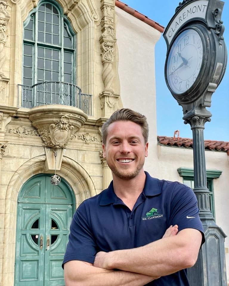 Anthony Grynchal in the Claremont Village near the theater facade and street clock at dusk