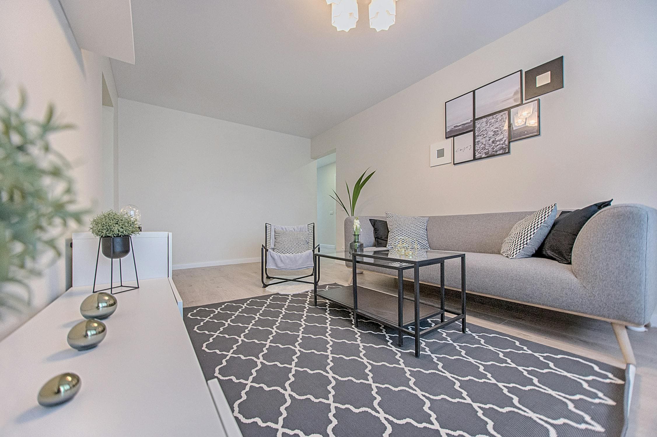 Staged living room with a gray sofa, patterned rug, and coordinated black-and-white decor