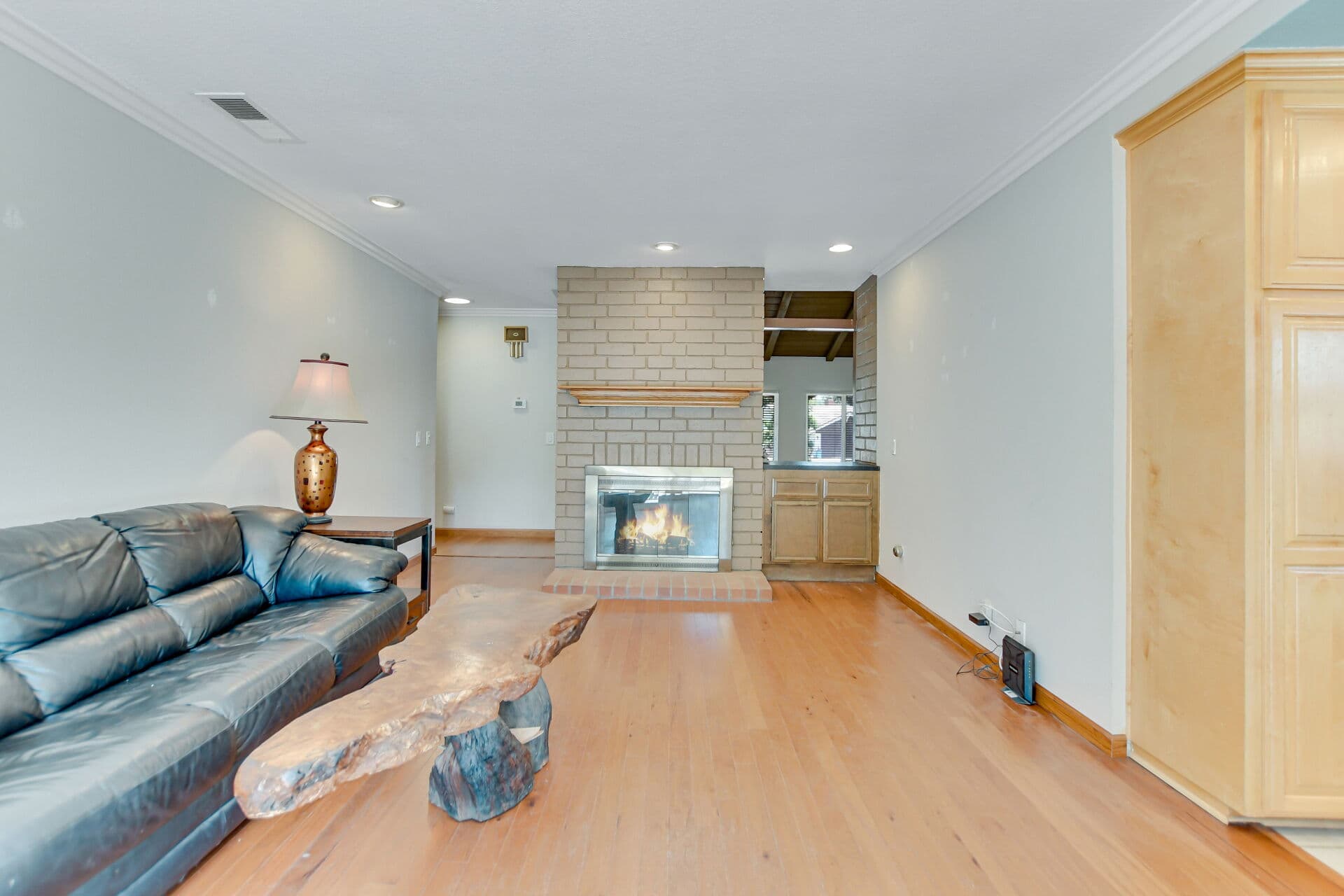 Claremont living room with a lit brick fireplace and adjoining wet bar area