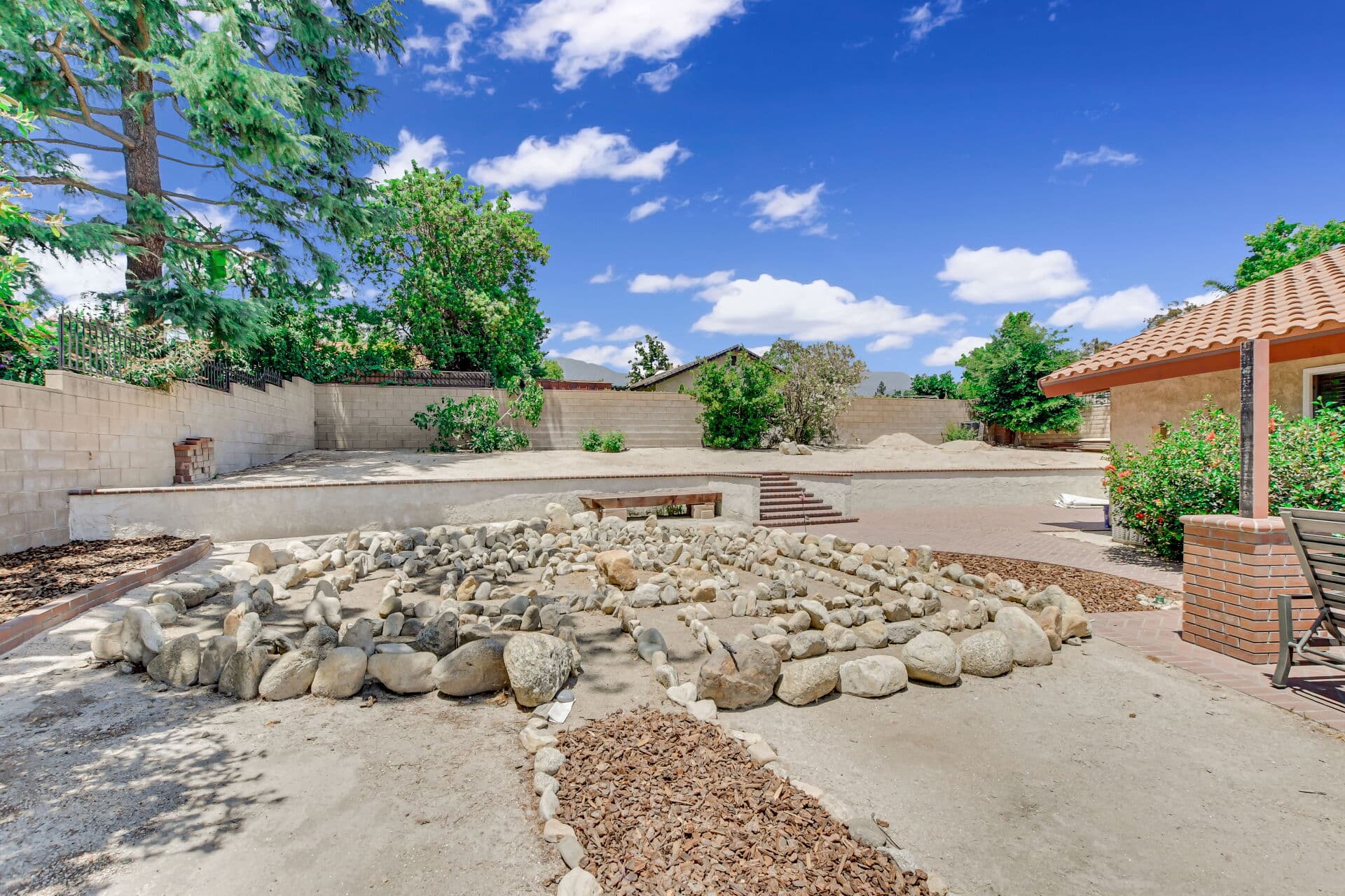 Walled Claremont backyard with block boundary fences and a river-rock landscape feature