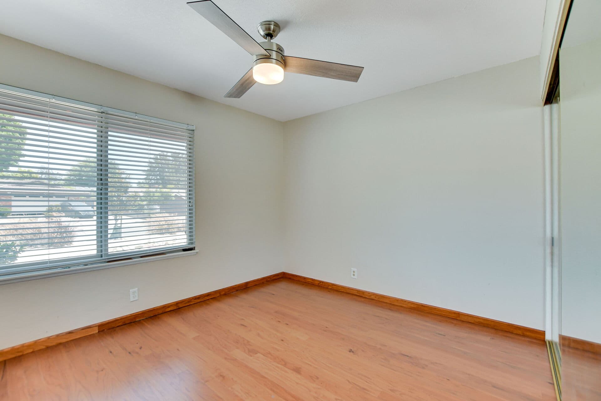 Vacant Claremont bedroom with wood floors, ceiling fan, and mirrored closet ready for a tenant