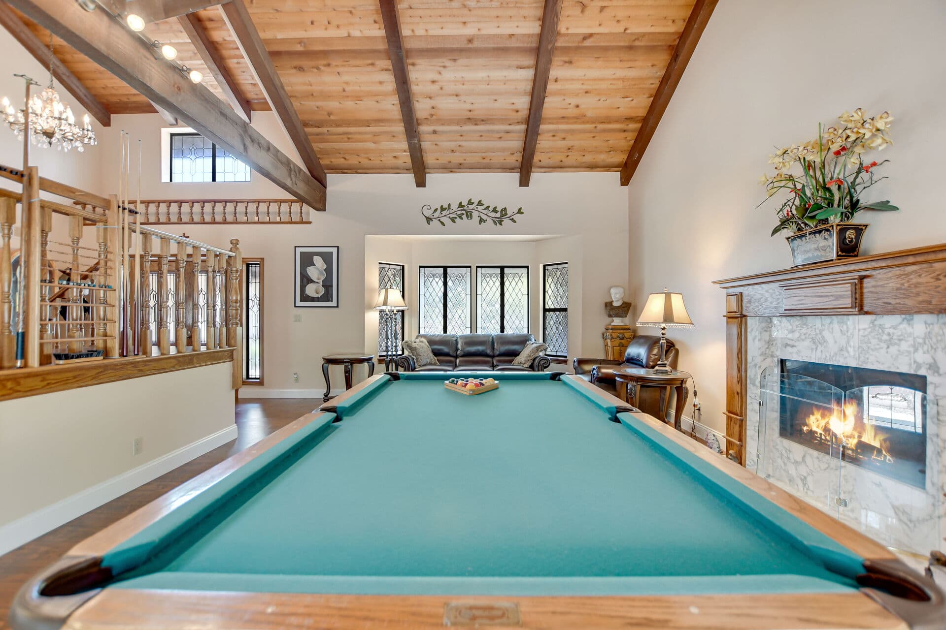 Great room with pool table, chandelier, and fireplace in a Claremont home