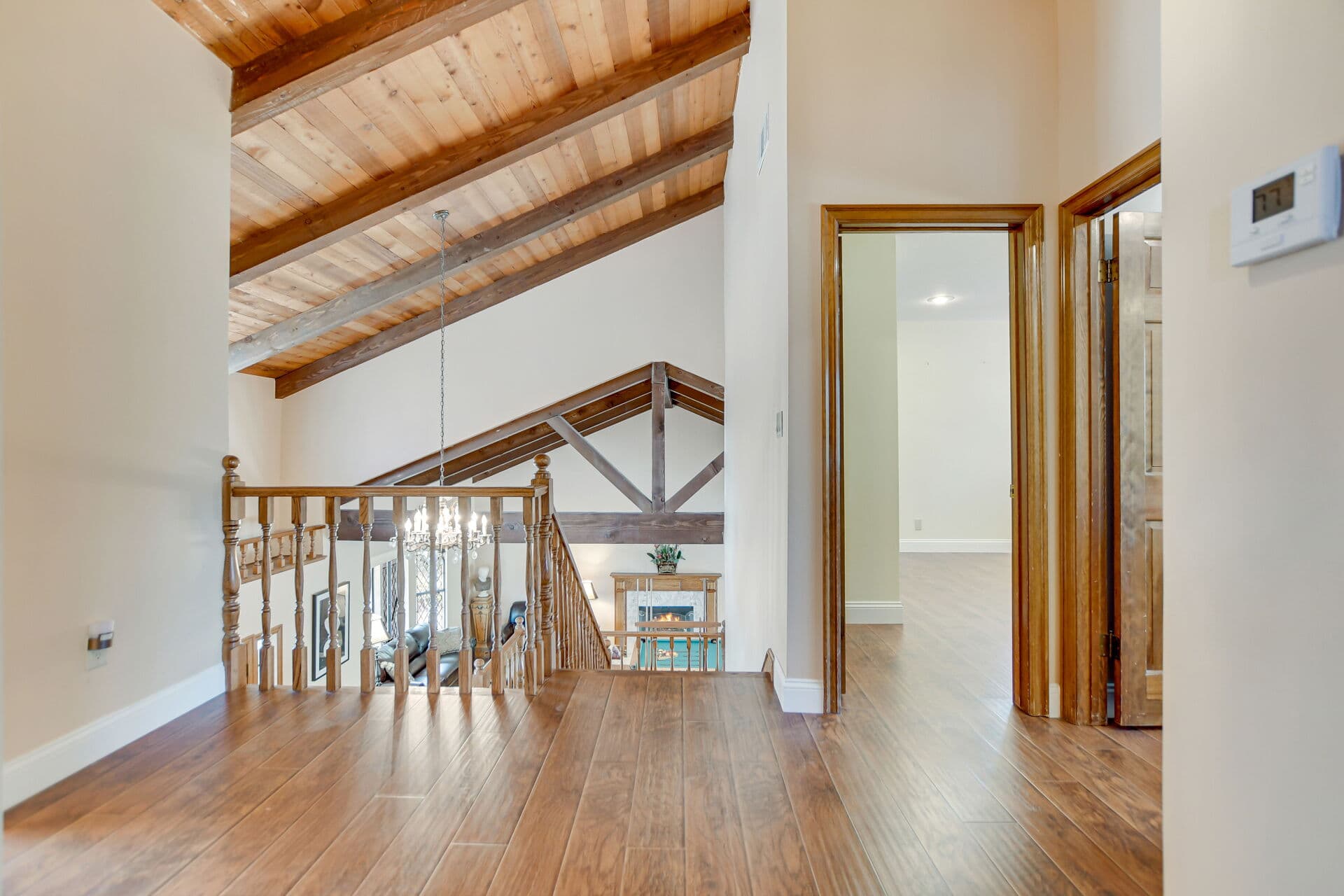 Upstairs landing with a vaulted beam ceiling and oak balustrade in an older Claremont home