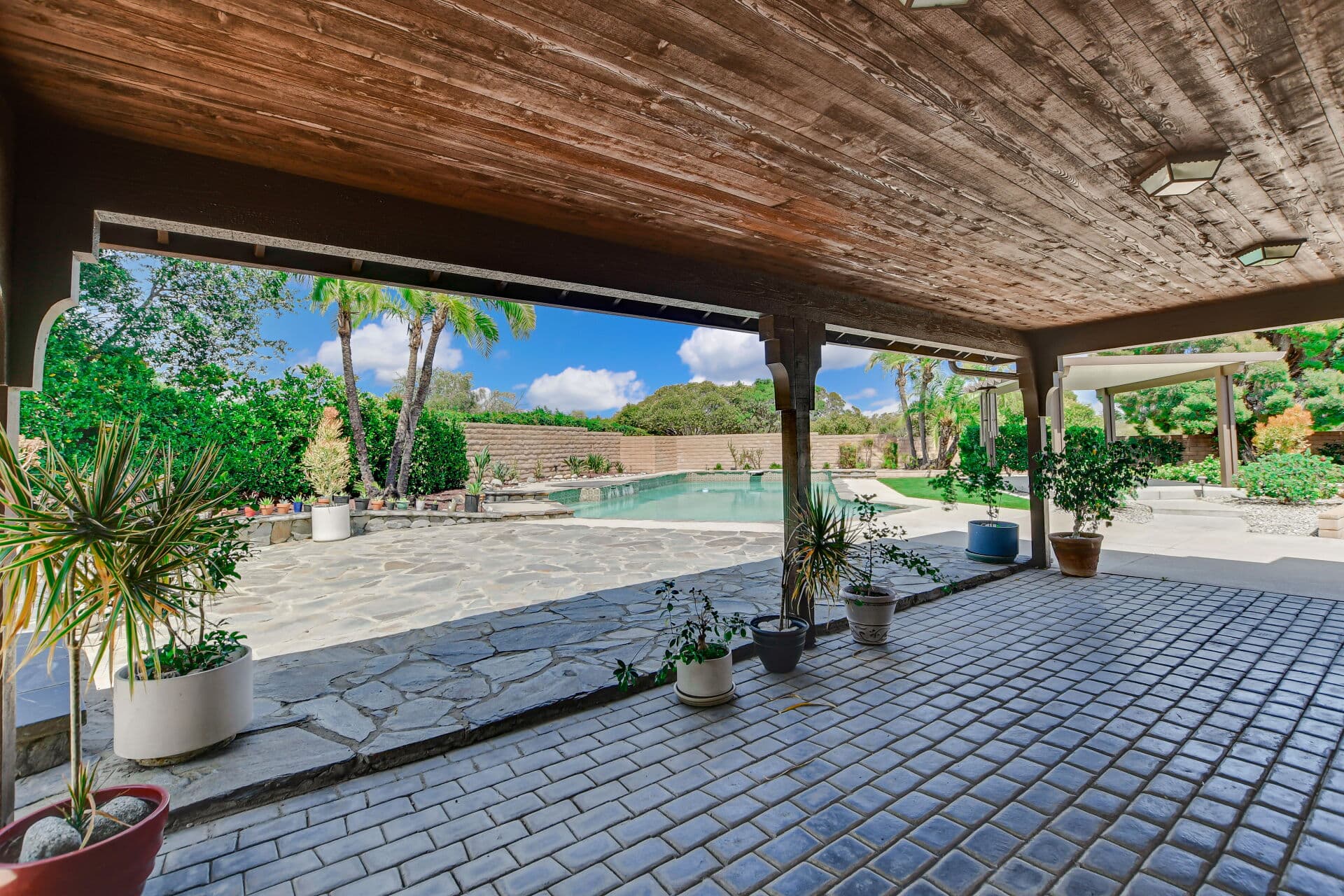Covered patio looking out to the pool and garden walls at a Claremont home