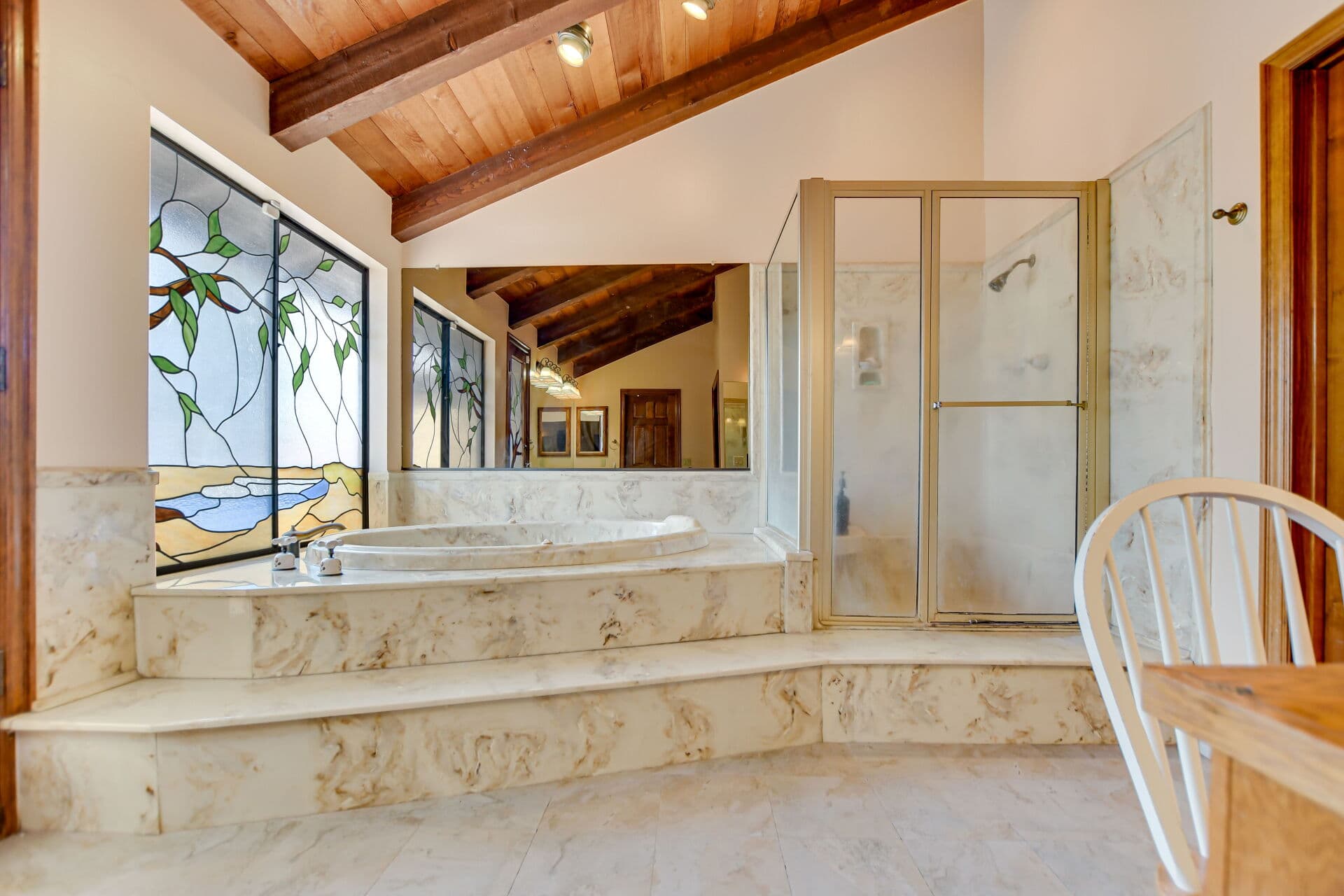 Primary bathroom with marble tub platform and stained glass in a Claremont home