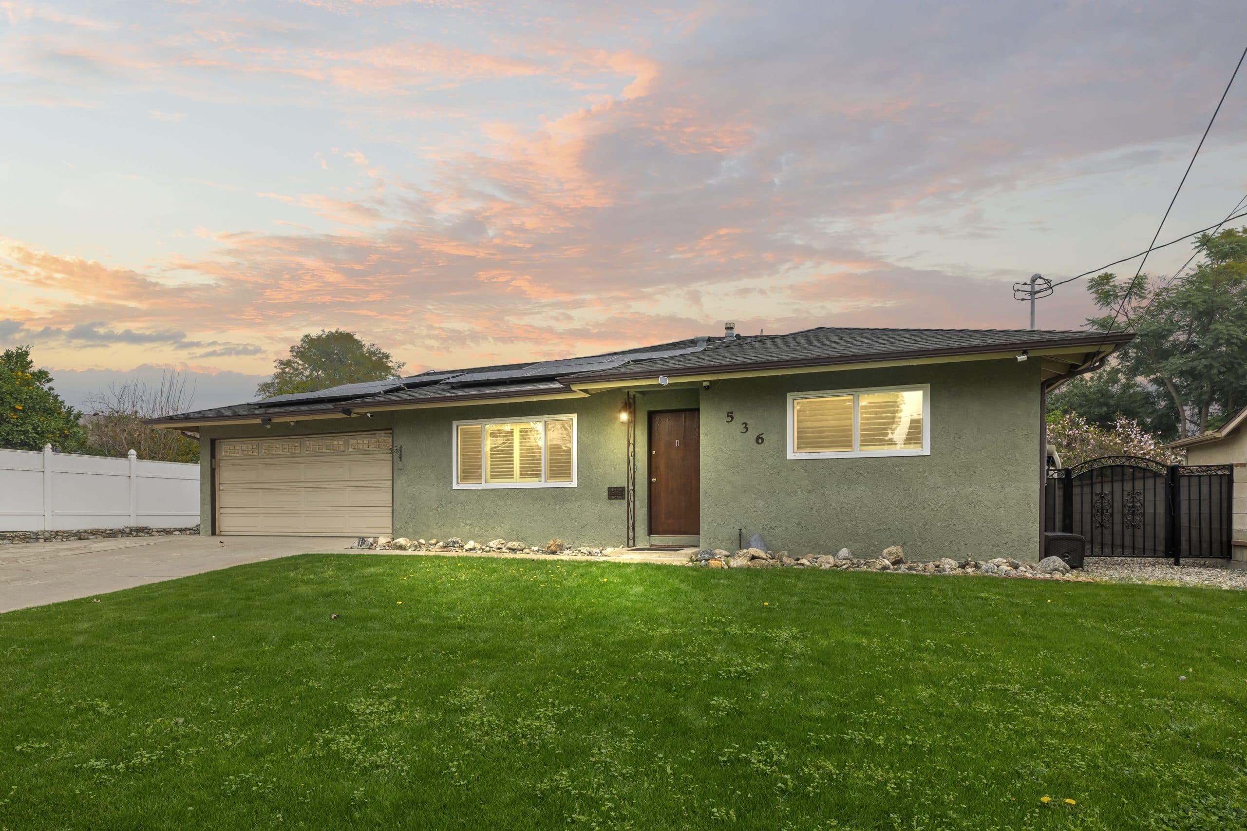 Claremont ranch home at golden hour with warmly lit windows and a fresh lawn
