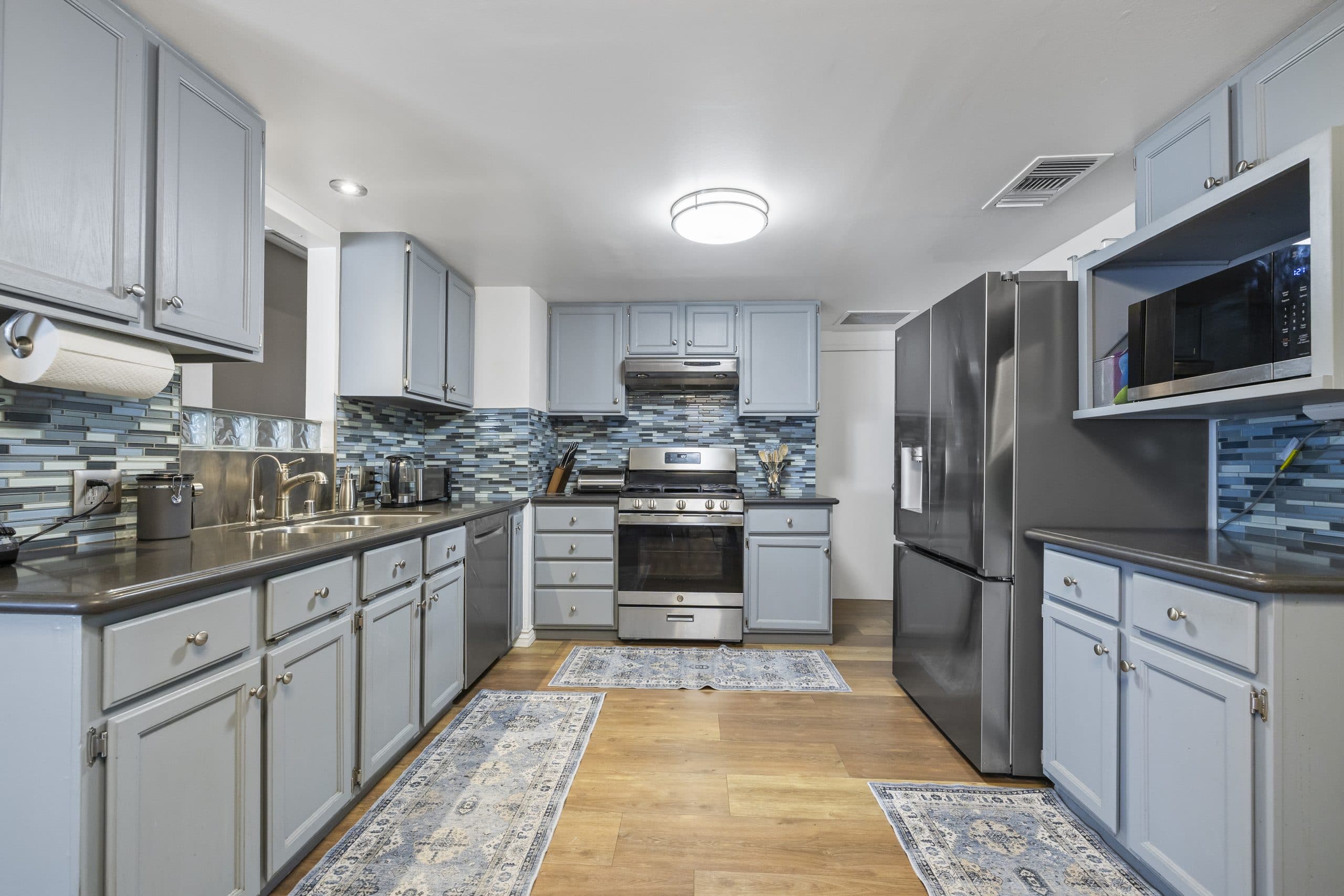 Renovated kitchen with blue cabinets and glass-tile backsplash in a Claremont home