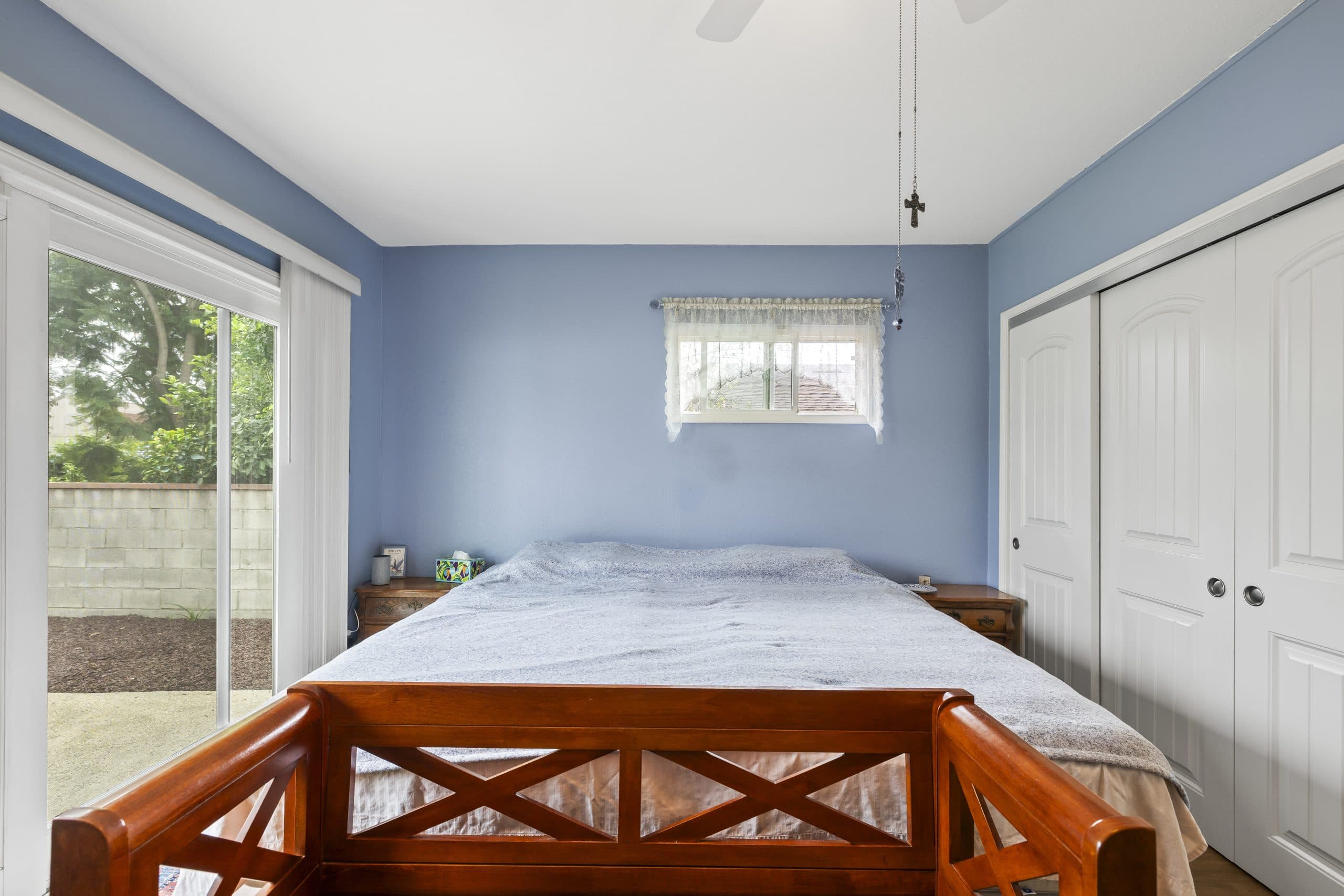 Bedroom with periwinkle walls and a slider to the yard in a Claremont home