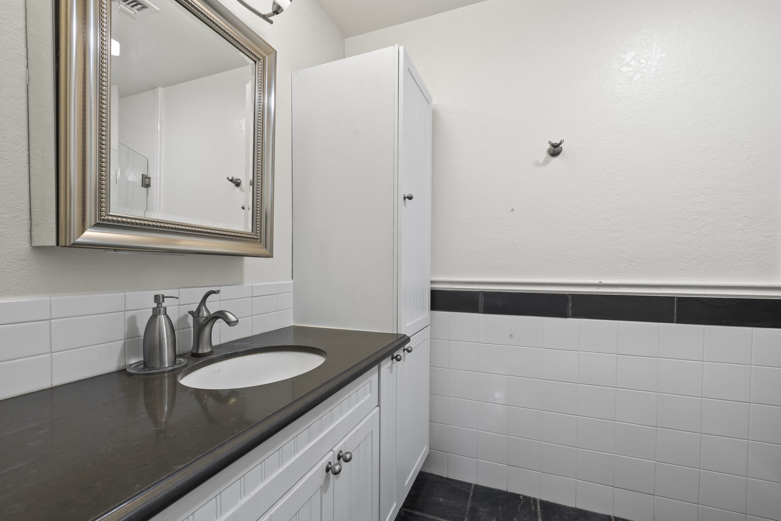 Bathroom vanity with a stone counter and beadboard cabinets in a Claremont home