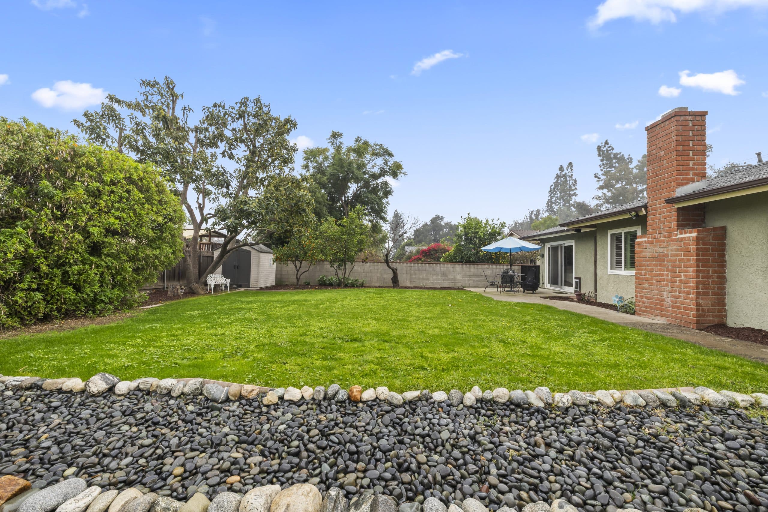 Fenced backyard of a Claremont home with a brick chimney and block wall