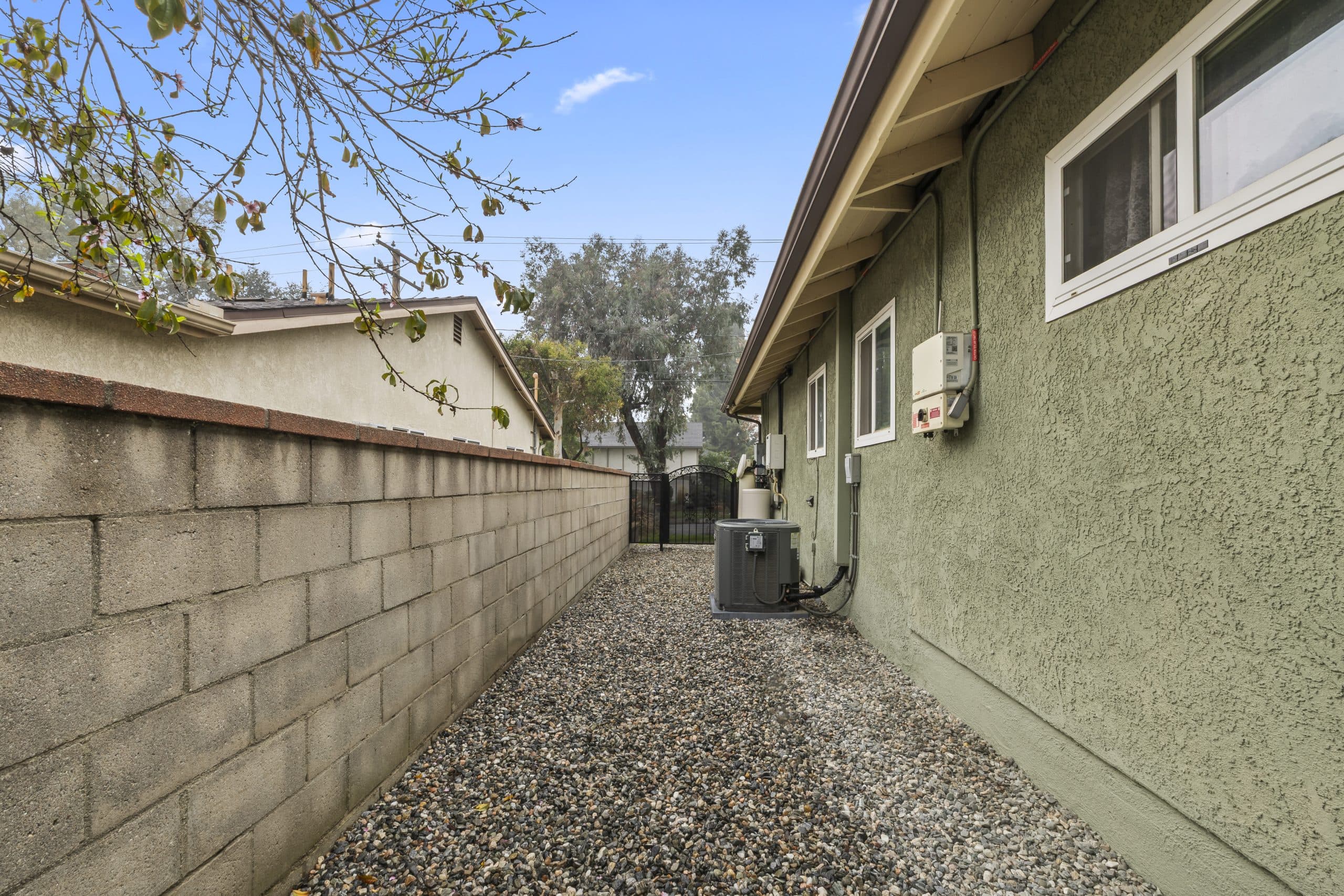 Side yard of a Claremont home showing the AC condenser and electrical equipment