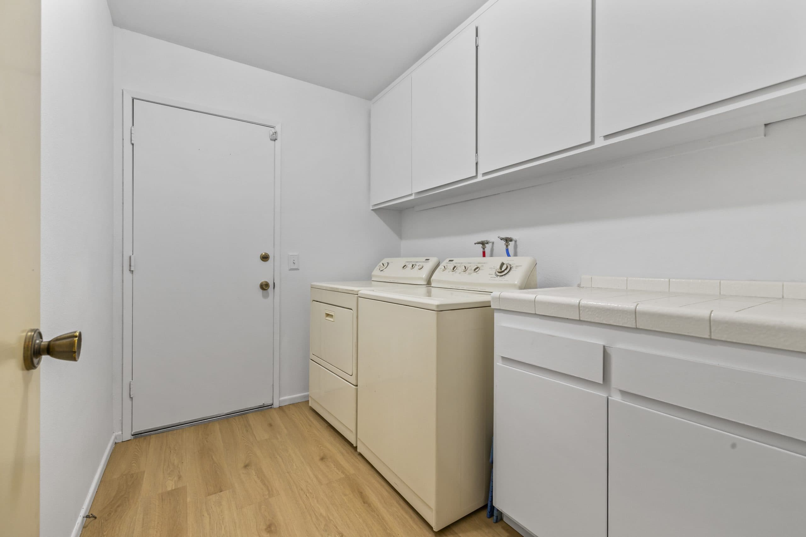 Laundry room with washer, dryer, and cabinets in a Claremont home