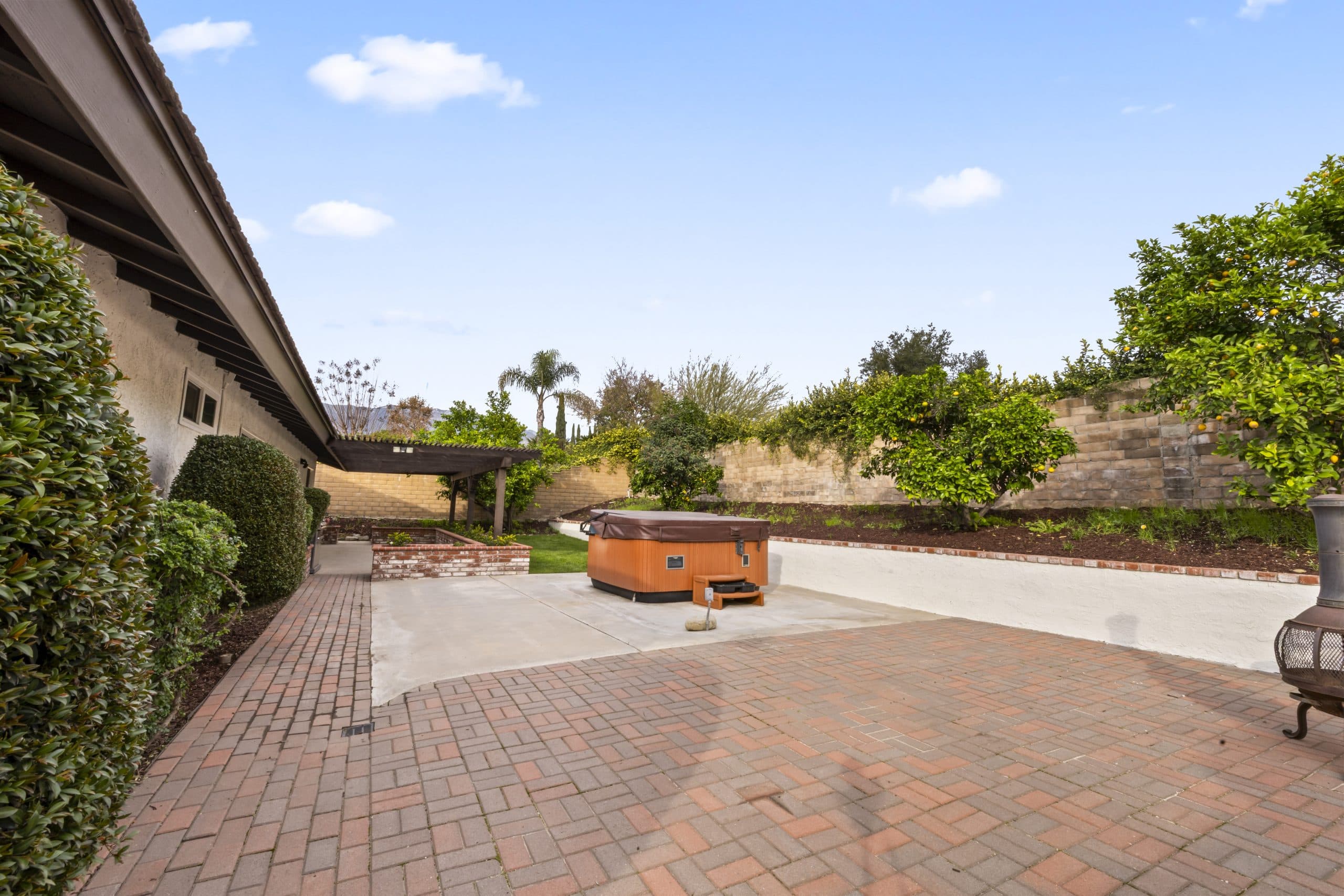 Terraced Claremont backyard with a paver patio, spa, and citrus trees