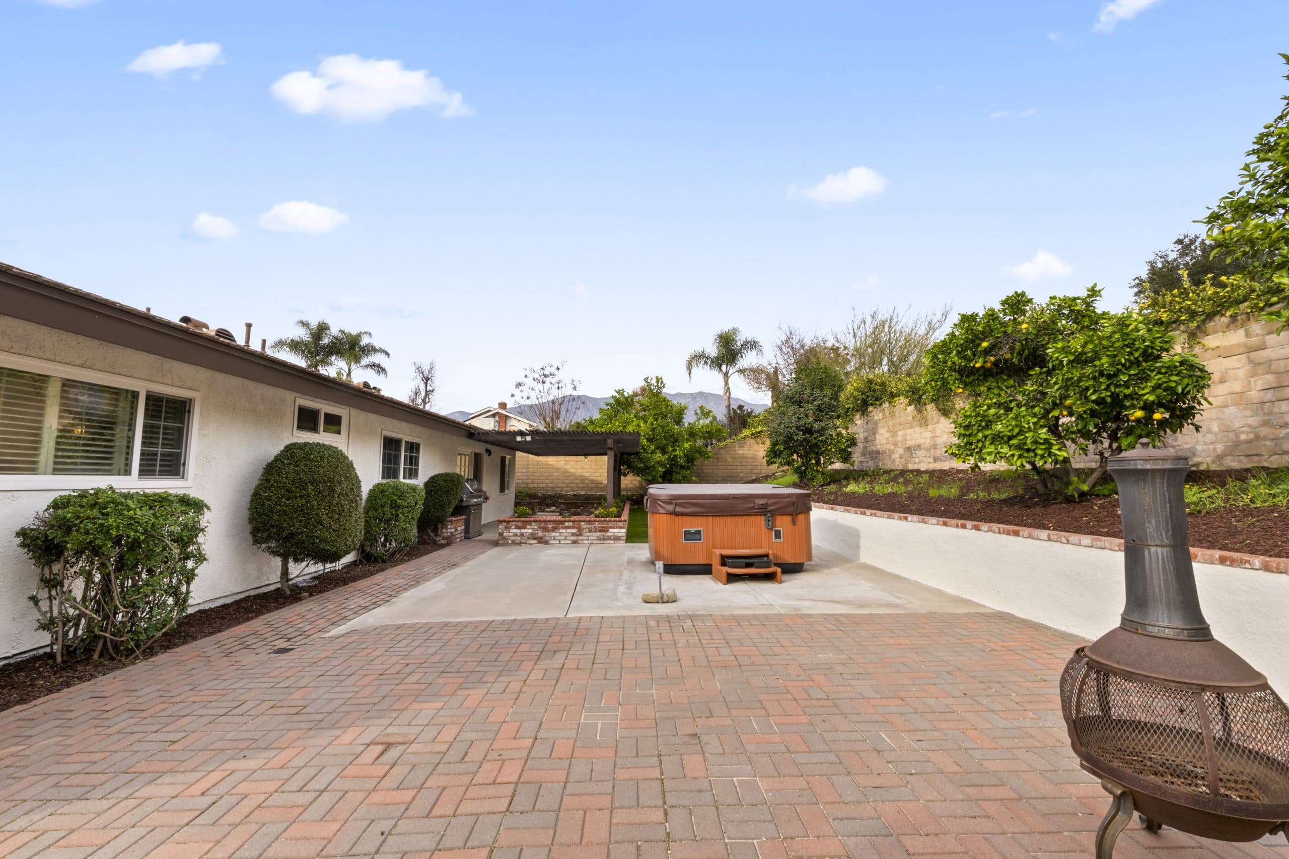 Brick-paved backyard courtyard with a covered spa at a Claremont home