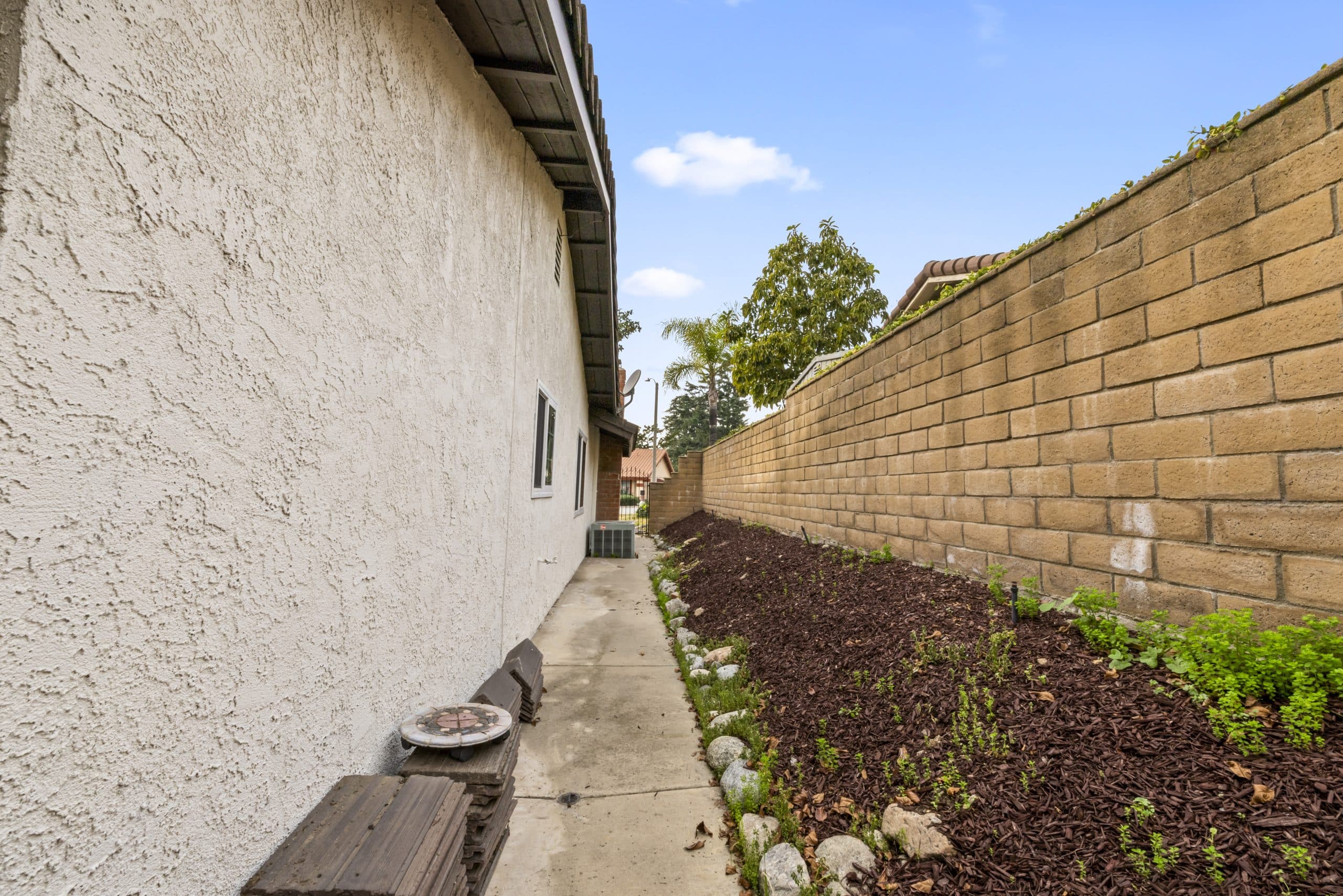 Side-yard garden bed along the stucco wall of a Claremont home
