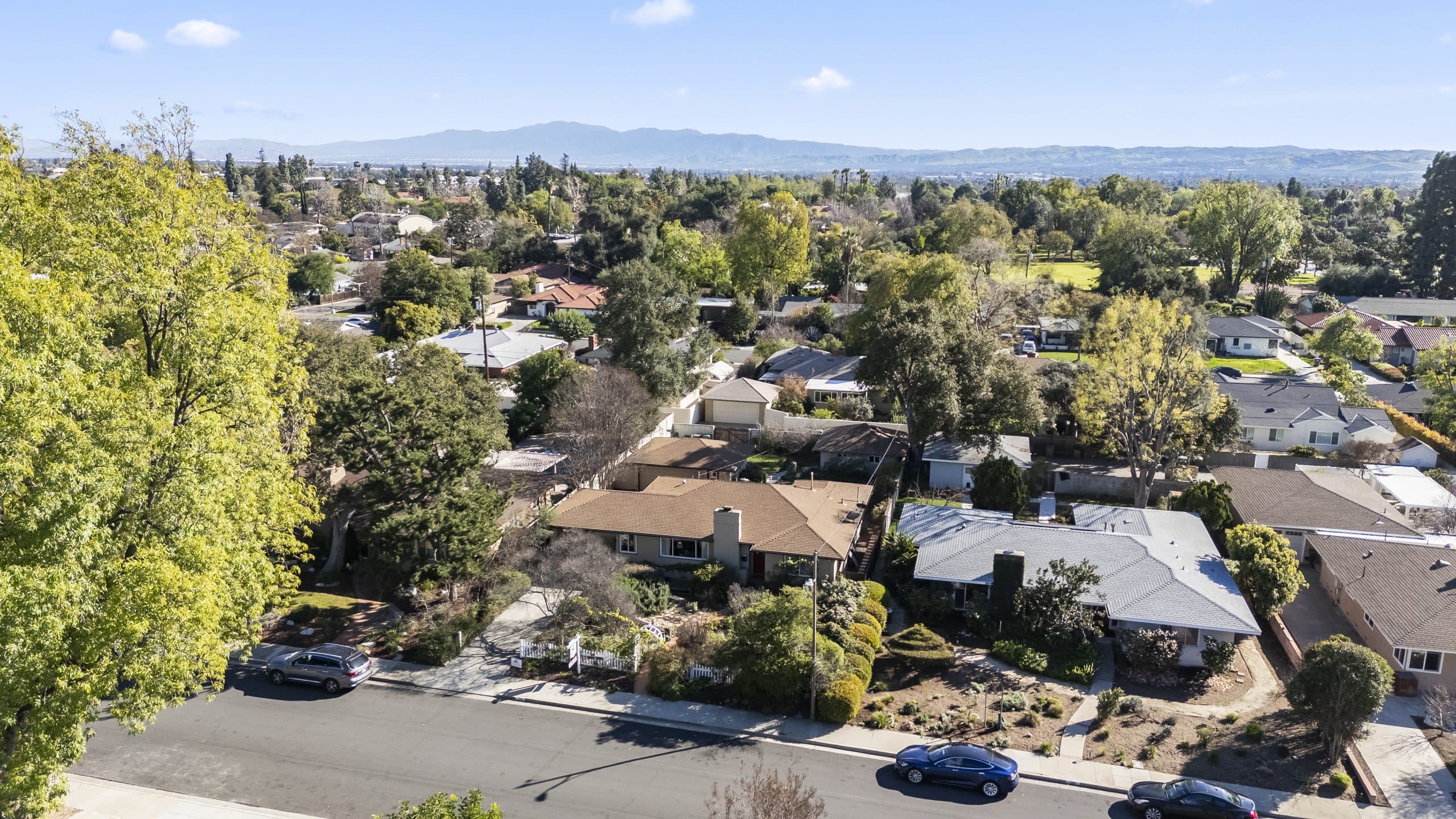 Aerial view of a tree-lined Claremont neighborhood with the San Gabriel Mountains behind