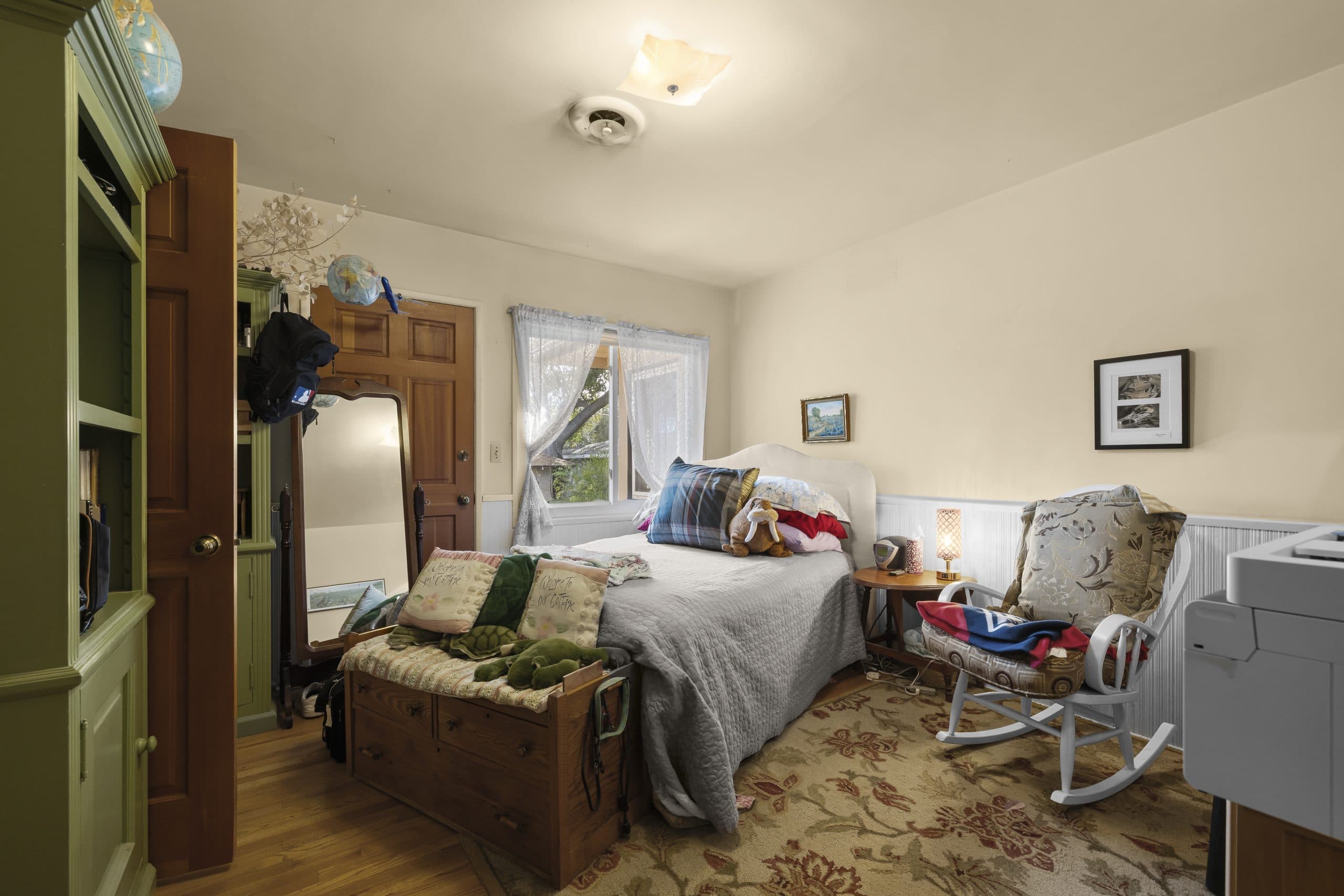 Cozy cottage bedroom in a smaller Claremont home with vintage furnishings and a rocking chair