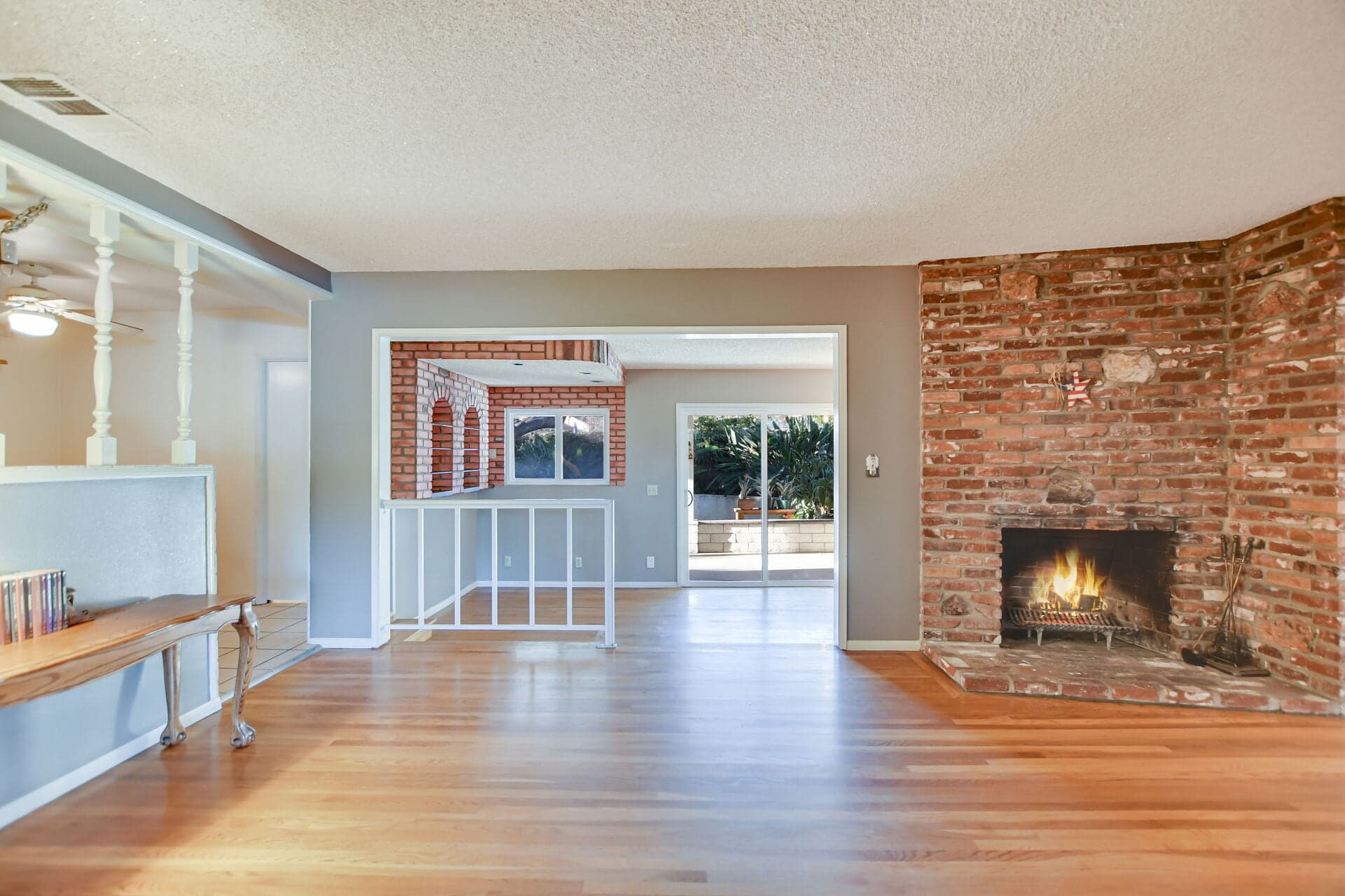 Empty move-in-ready Claremont living room with brick fireplace and hardwood floors