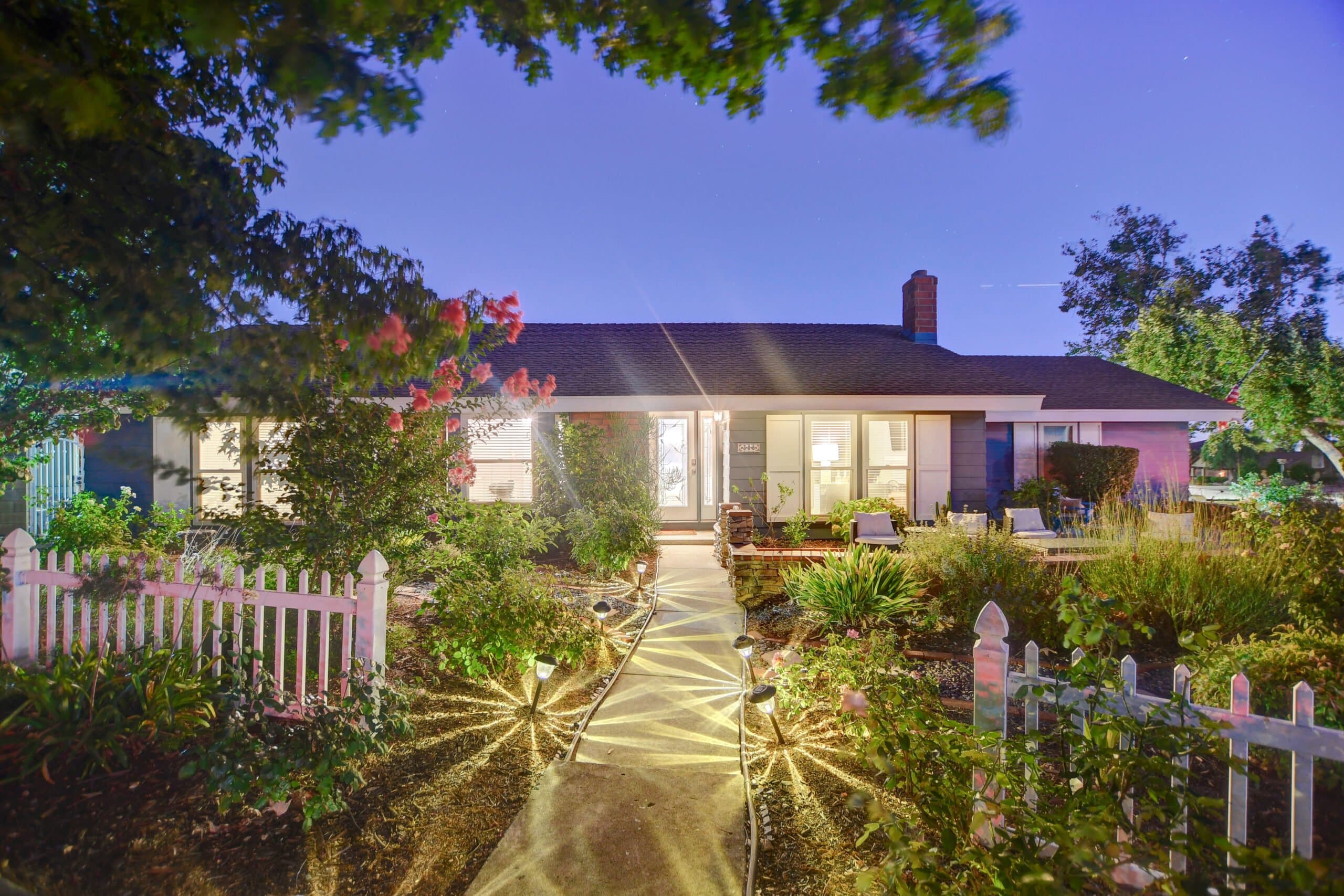 Claremont home at twilight with a lit walkway and picket fence