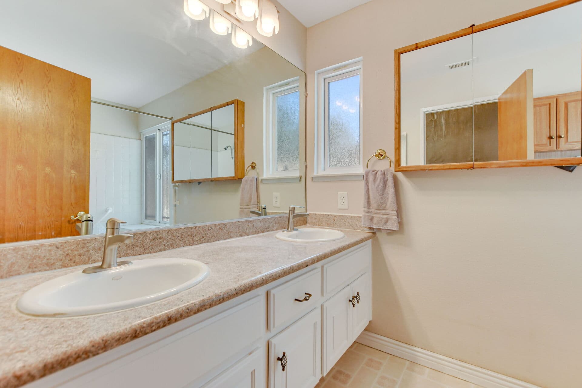 Double-vanity bathroom with oak mirrors in a Claremont home