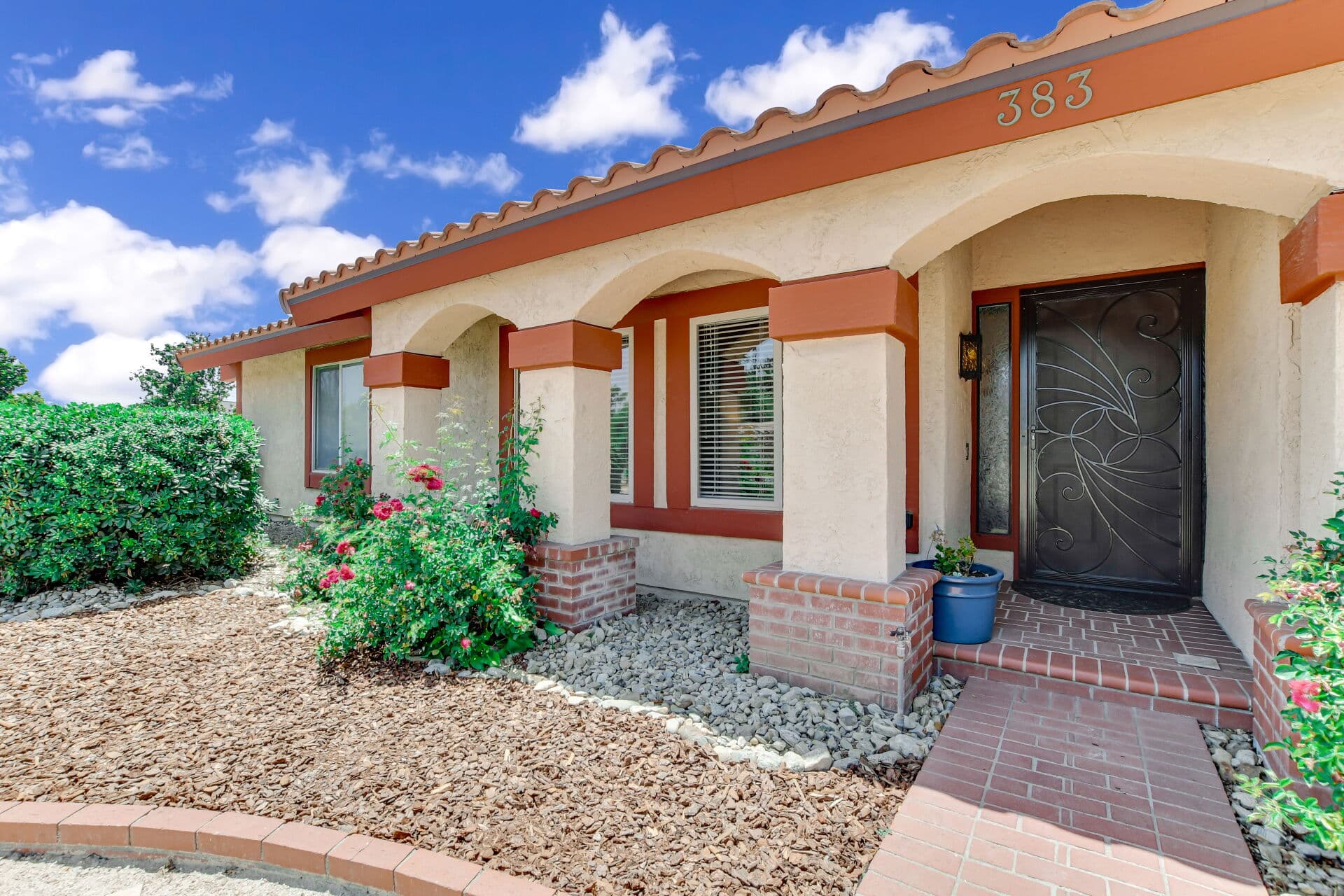 Welcoming arched front entry of a Spanish-style Claremont home with roses