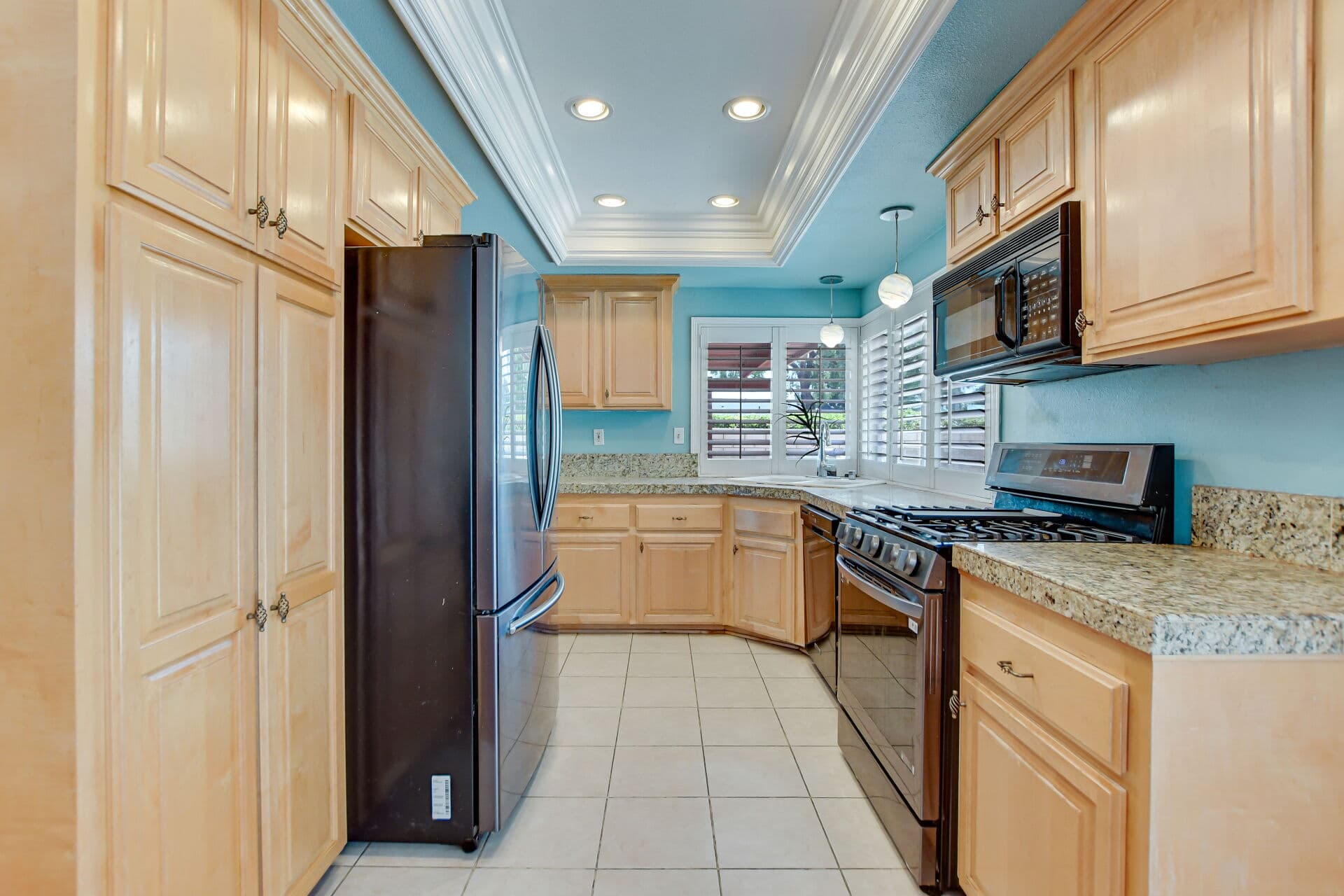 Galley kitchen with maple cabinets and plantation shutters in a Claremont home