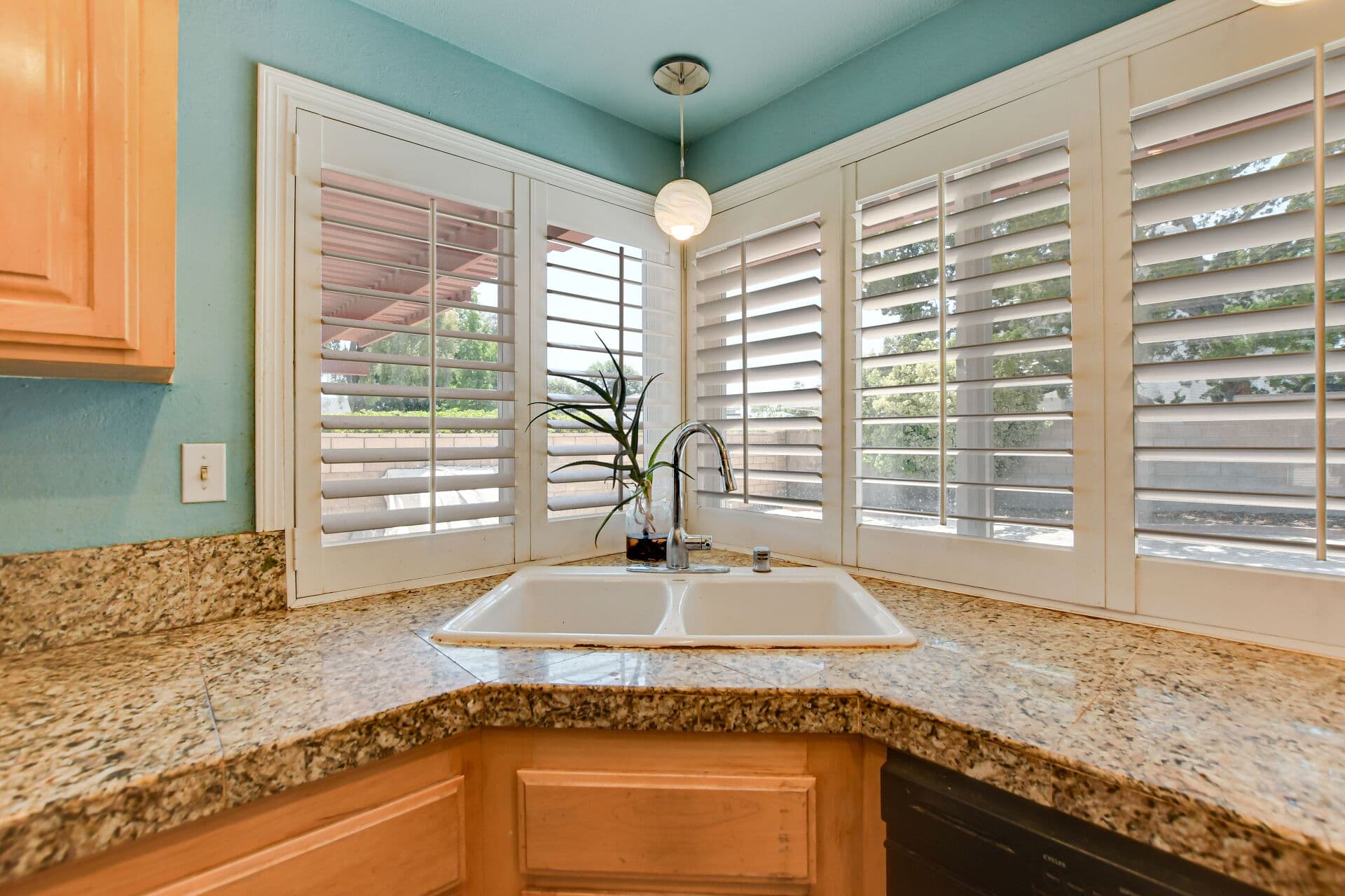 Kitchen corner sink with plantation shutters and a garden view in a Claremont home