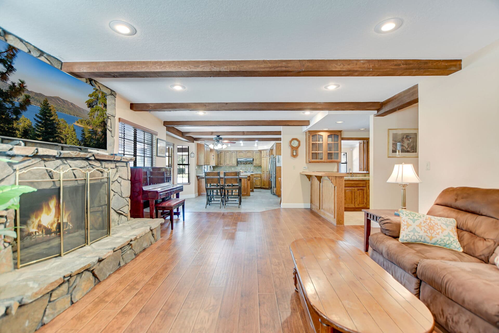 Family room with stone fireplace opening to the kitchen in a Claremont home