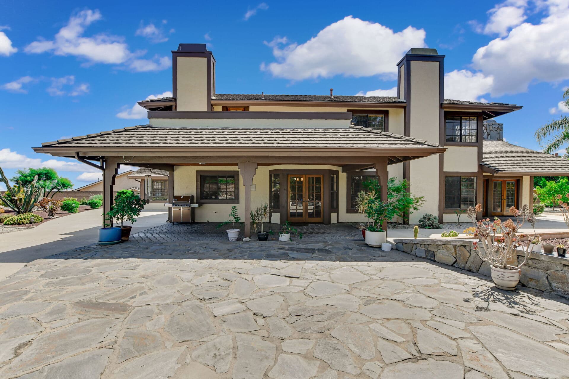 Rear exterior of a Claremont home with flagstone patio and potted plants