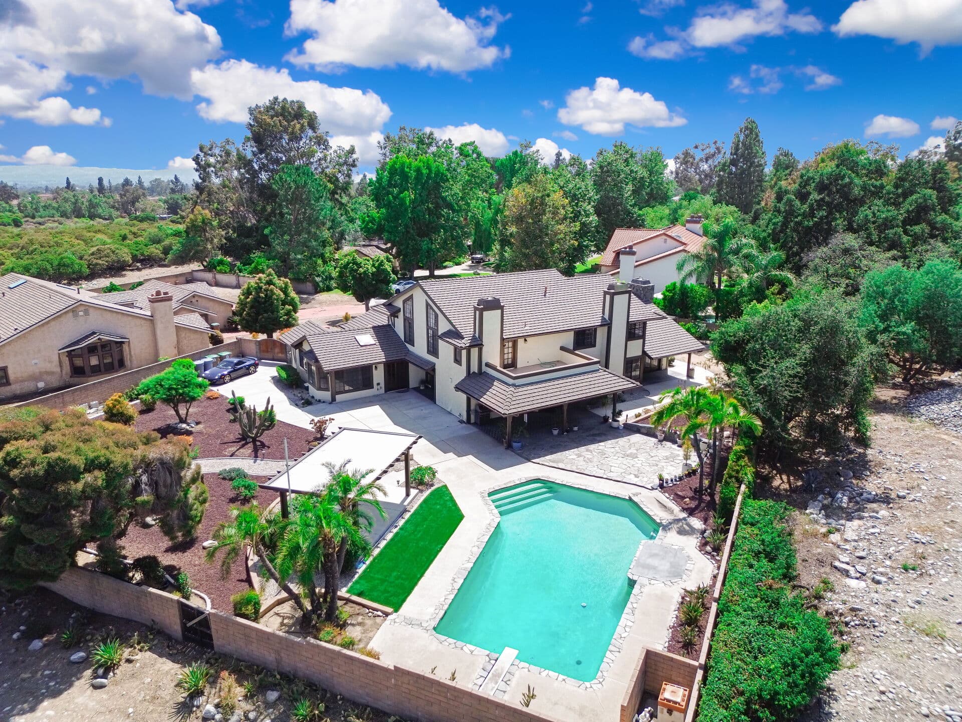 Aerial view over the backyard and pool of a Claremont home amid tree canopy