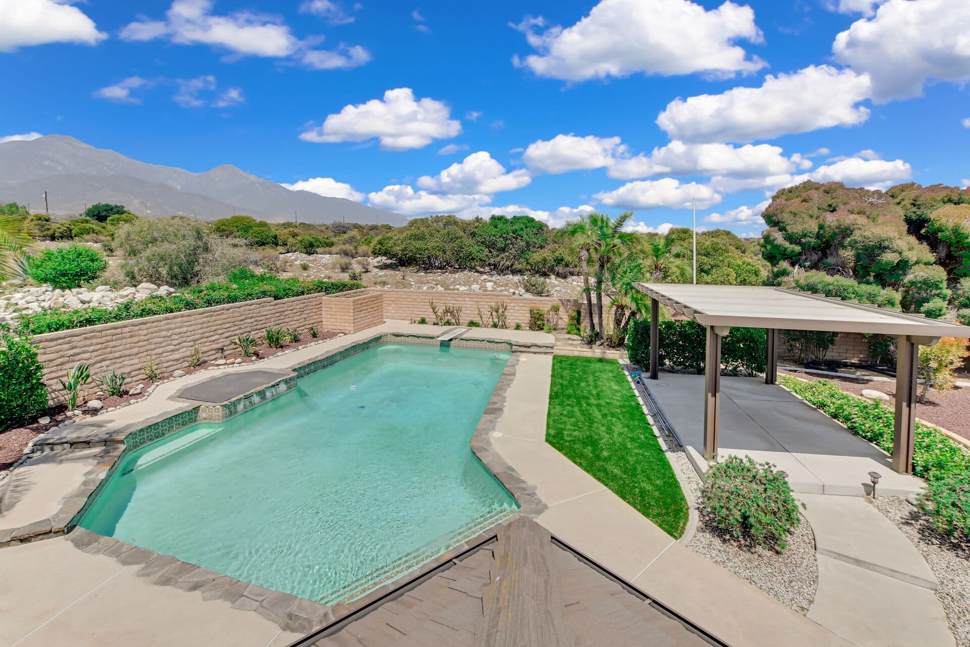 Elevated view of a Claremont backyard pool with mountains and a spring sky