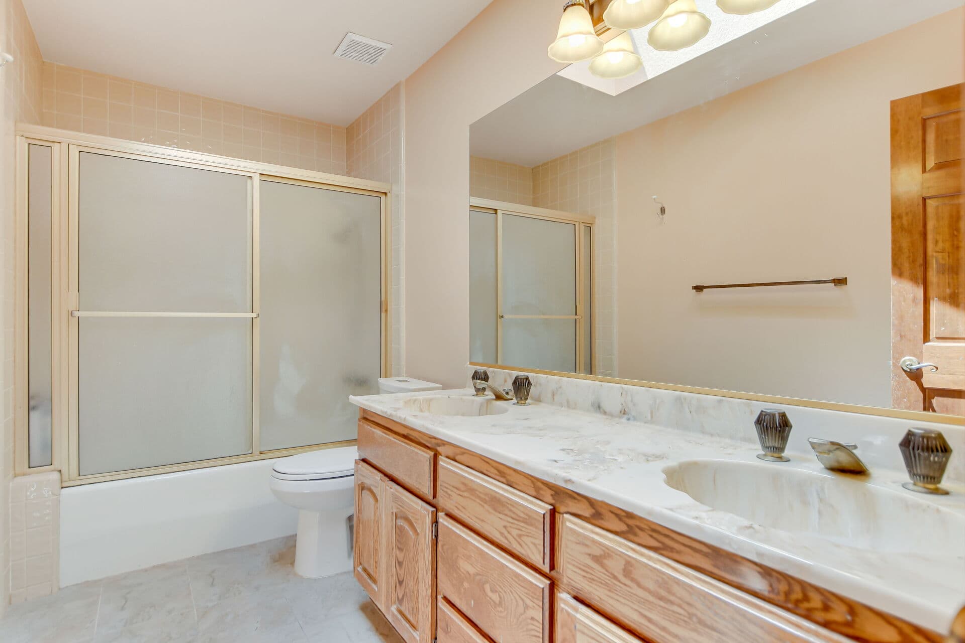 Original-condition Claremont bathroom with dated double vanity, the kind of finish an as-is sale leaves untouched