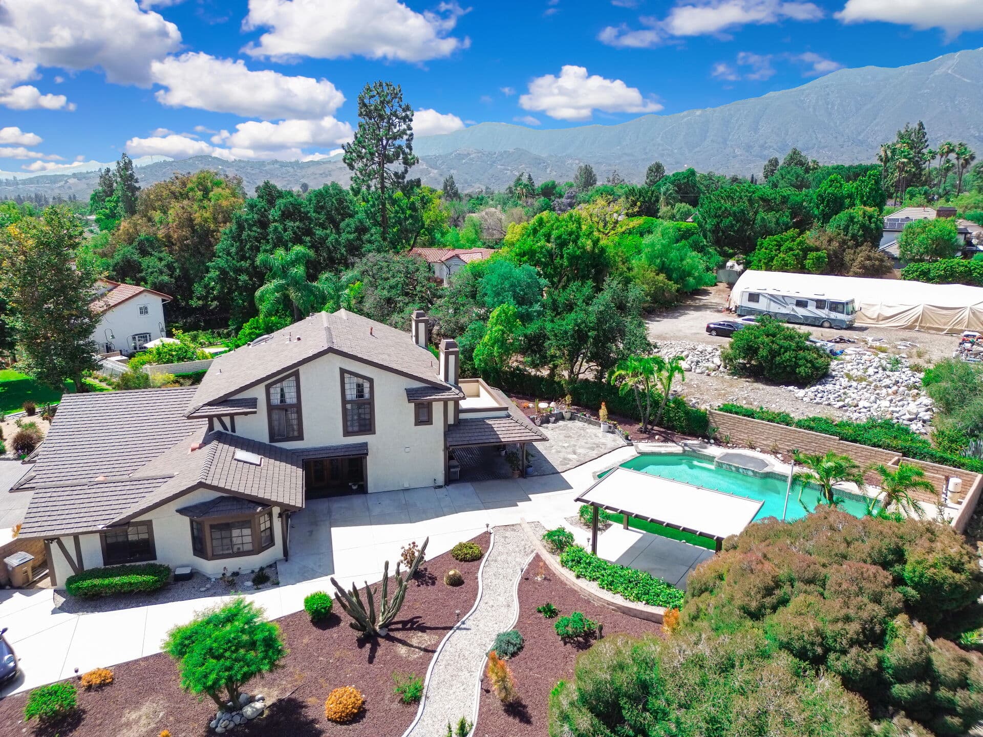 Aerial view of a foothill Claremont property beside a rocky wash, with the San Gabriel Mountains behind