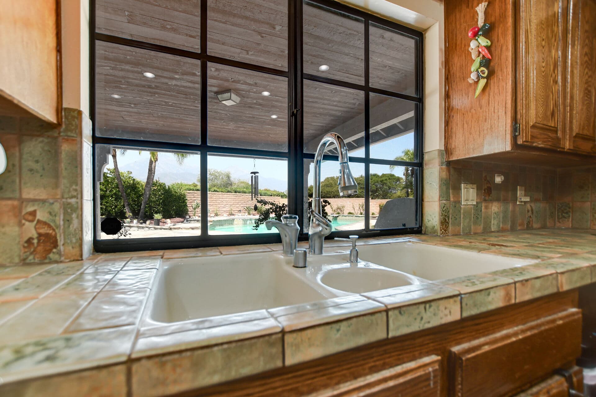 Claremont kitchen window framing a backyard pool with the San Gabriel Mountains in the distance