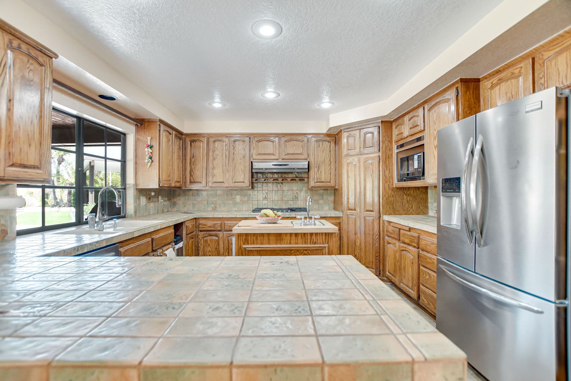 Kitchen with a tile peninsula and garden window in a Claremont home