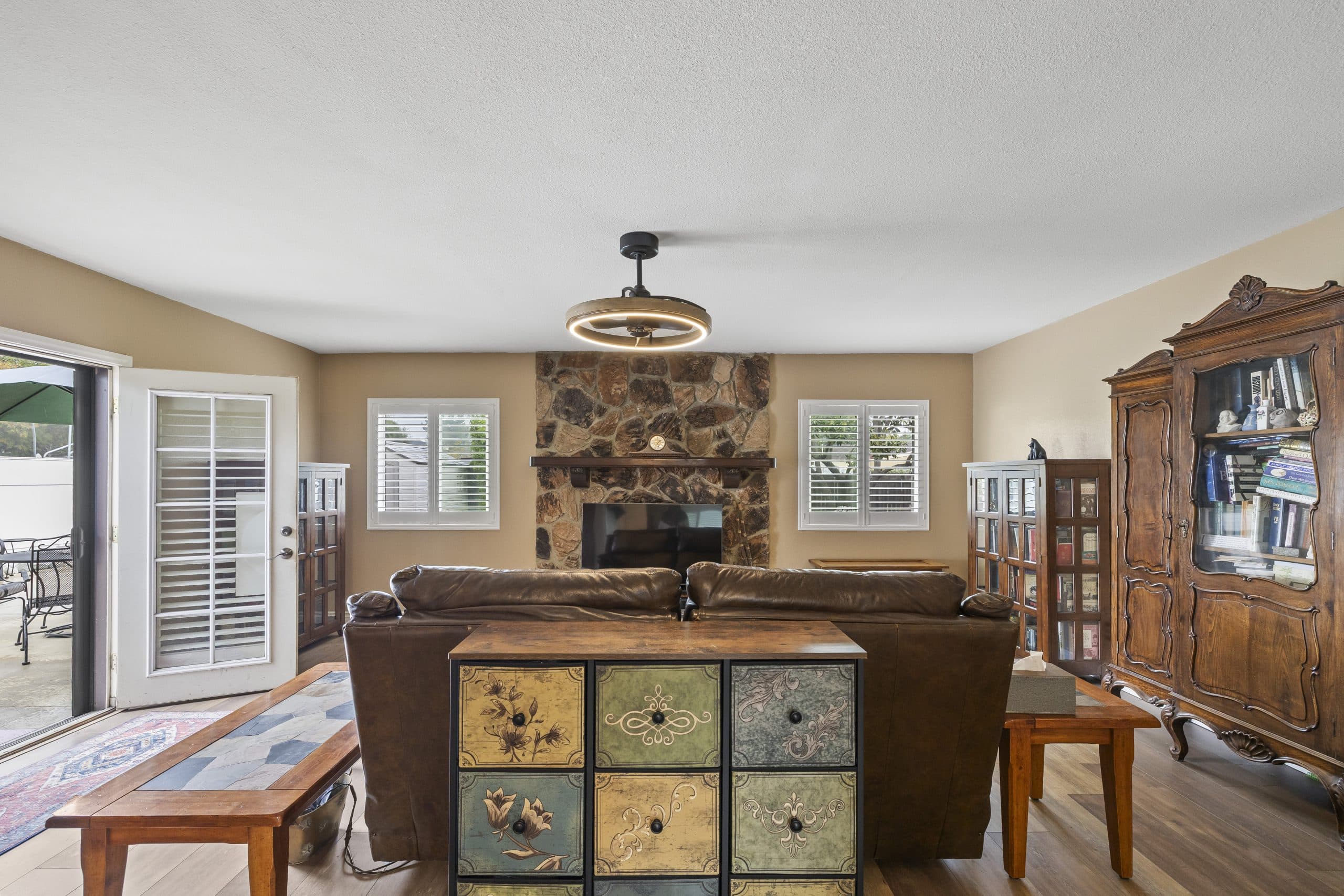 Warm Claremont family room with stone fireplace and antique book armoire