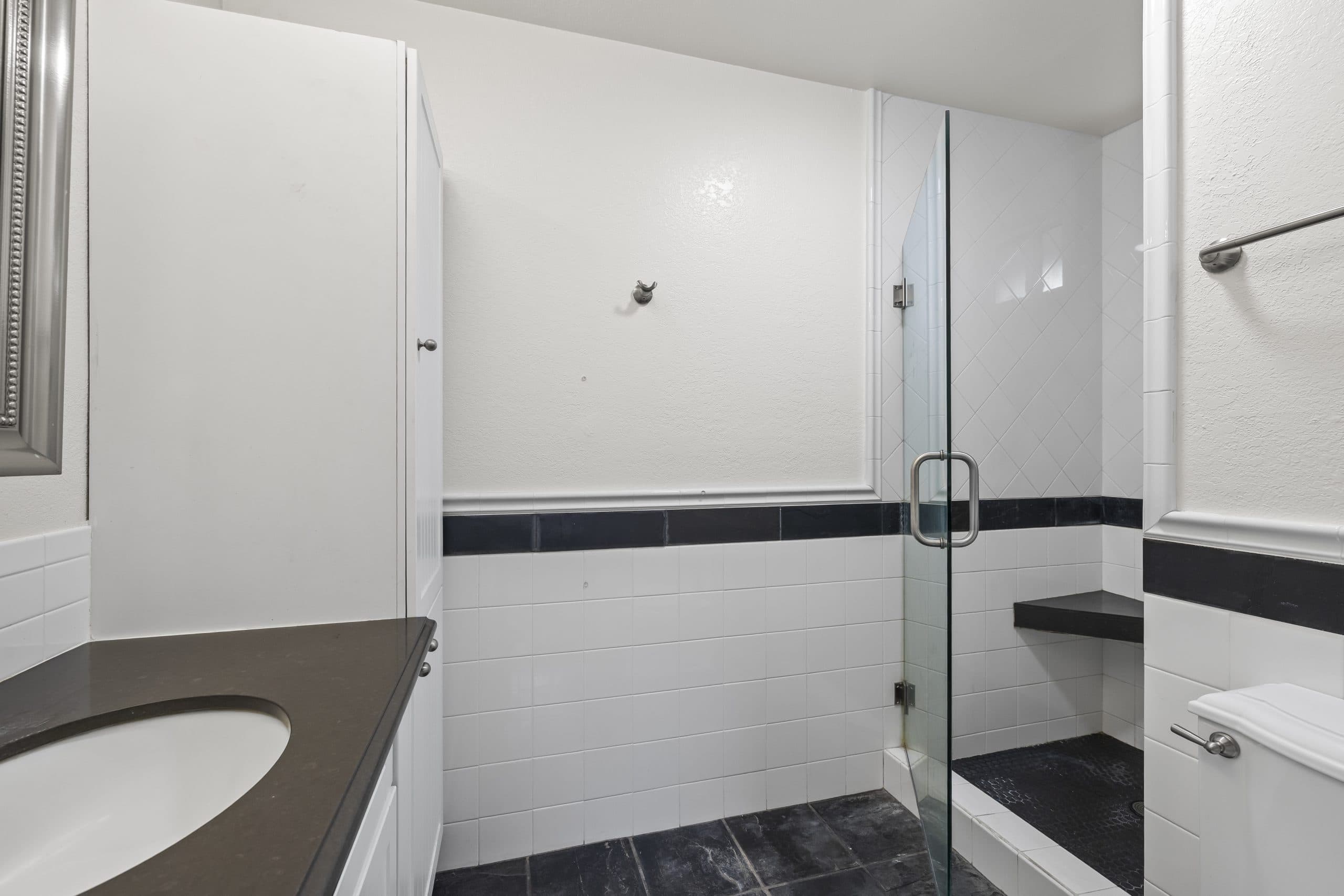 Walk-in frameless shower with built-in corner bench in a Claremont bathroom