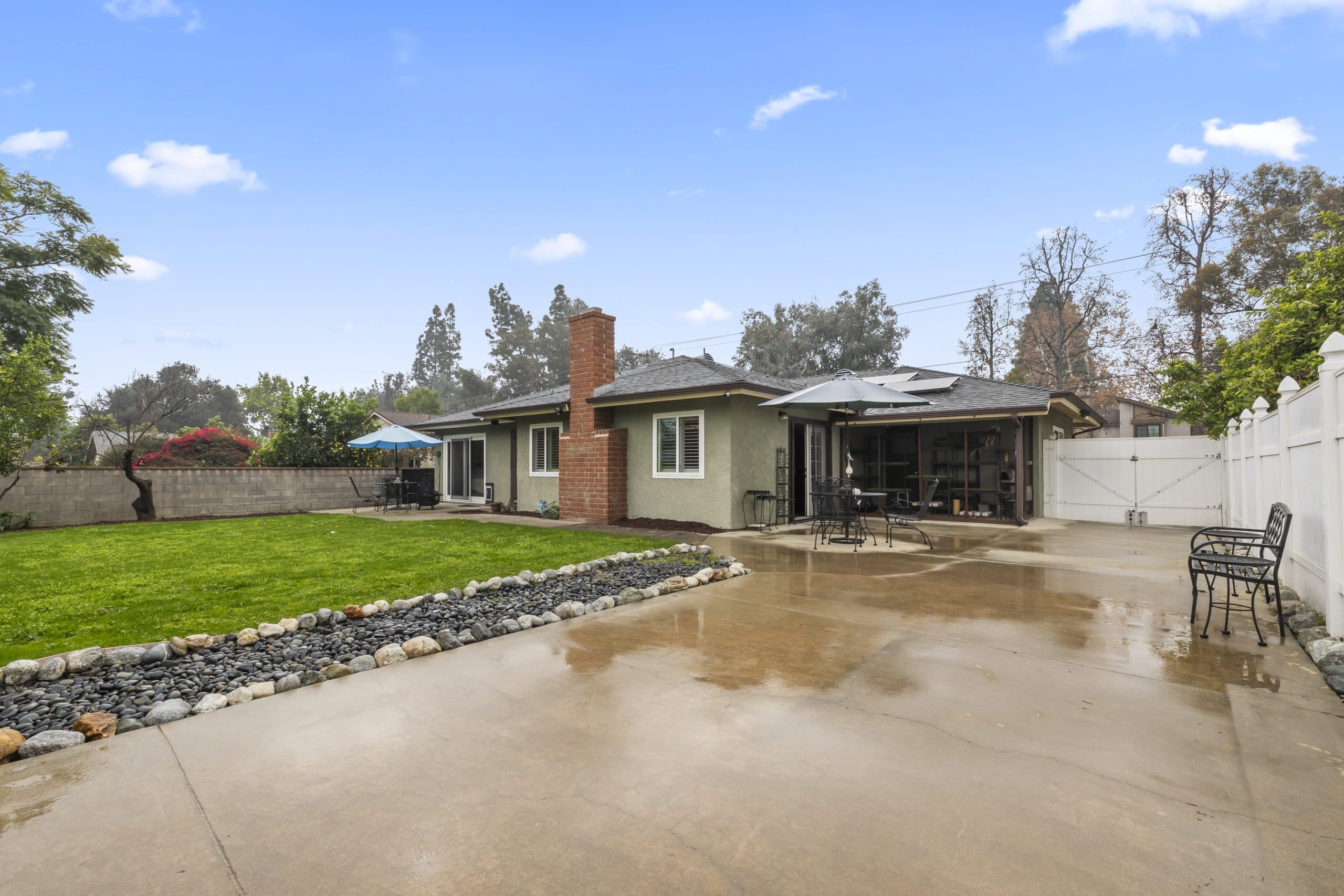 Rear exterior of a Claremont ranch home with a brick chimney and clean patio