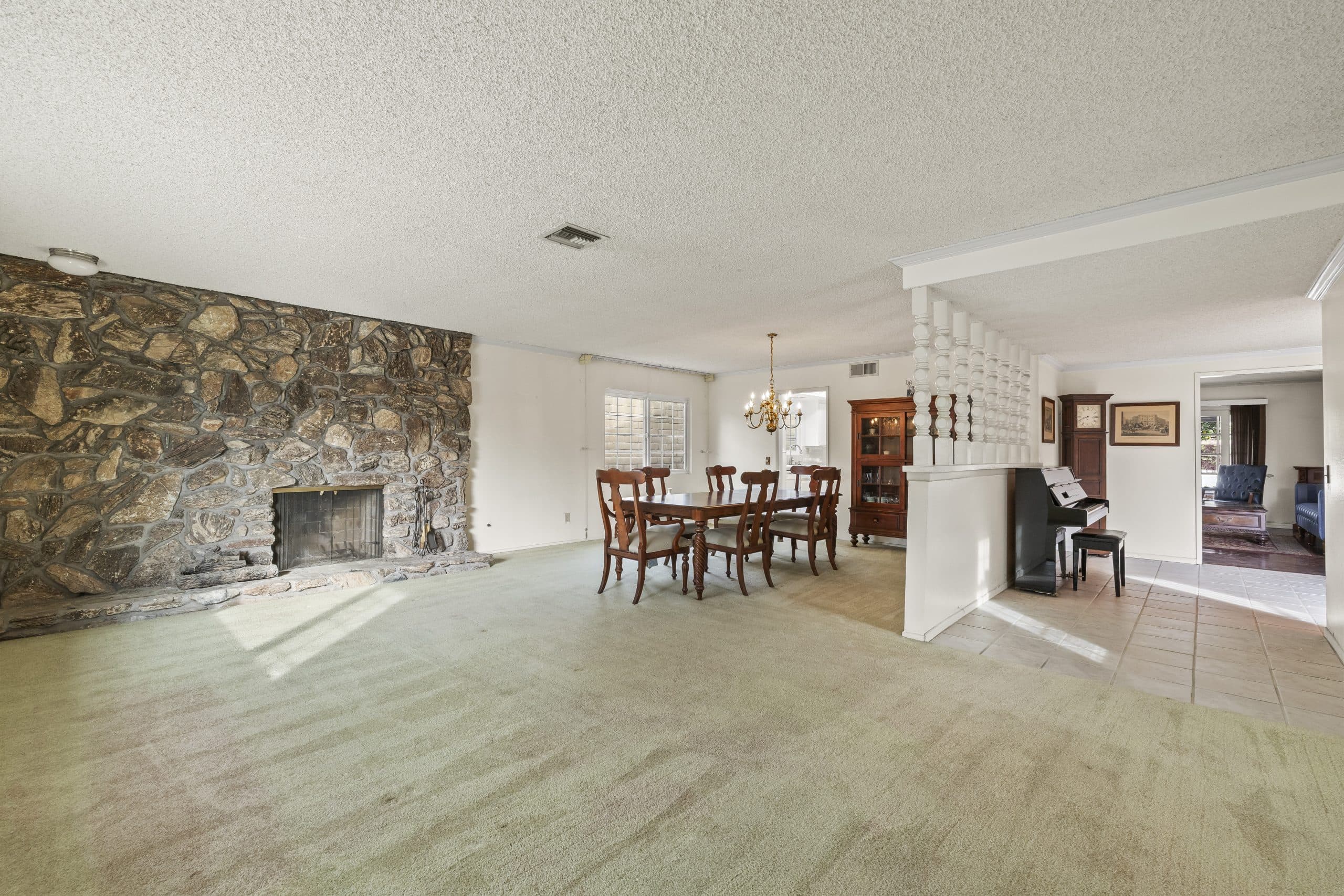 Formal living and dining room with a stone fireplace wall in a Claremont home
