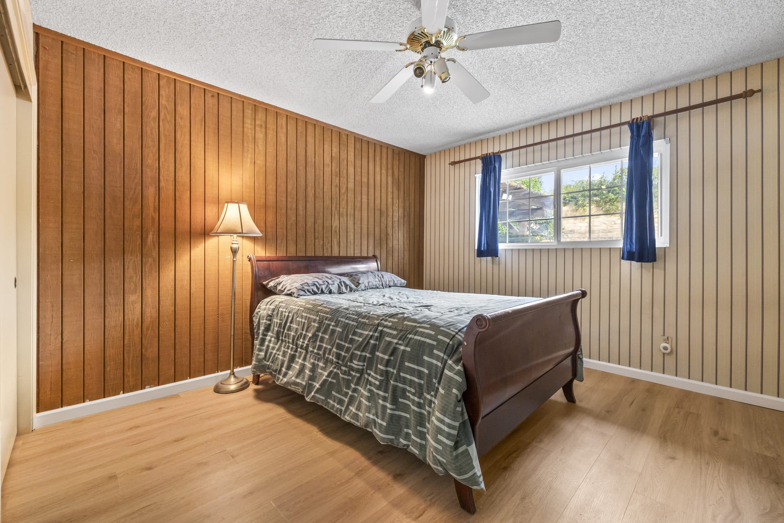 Wood-paneled bedroom with a mahogany sleigh bed in a Claremont home