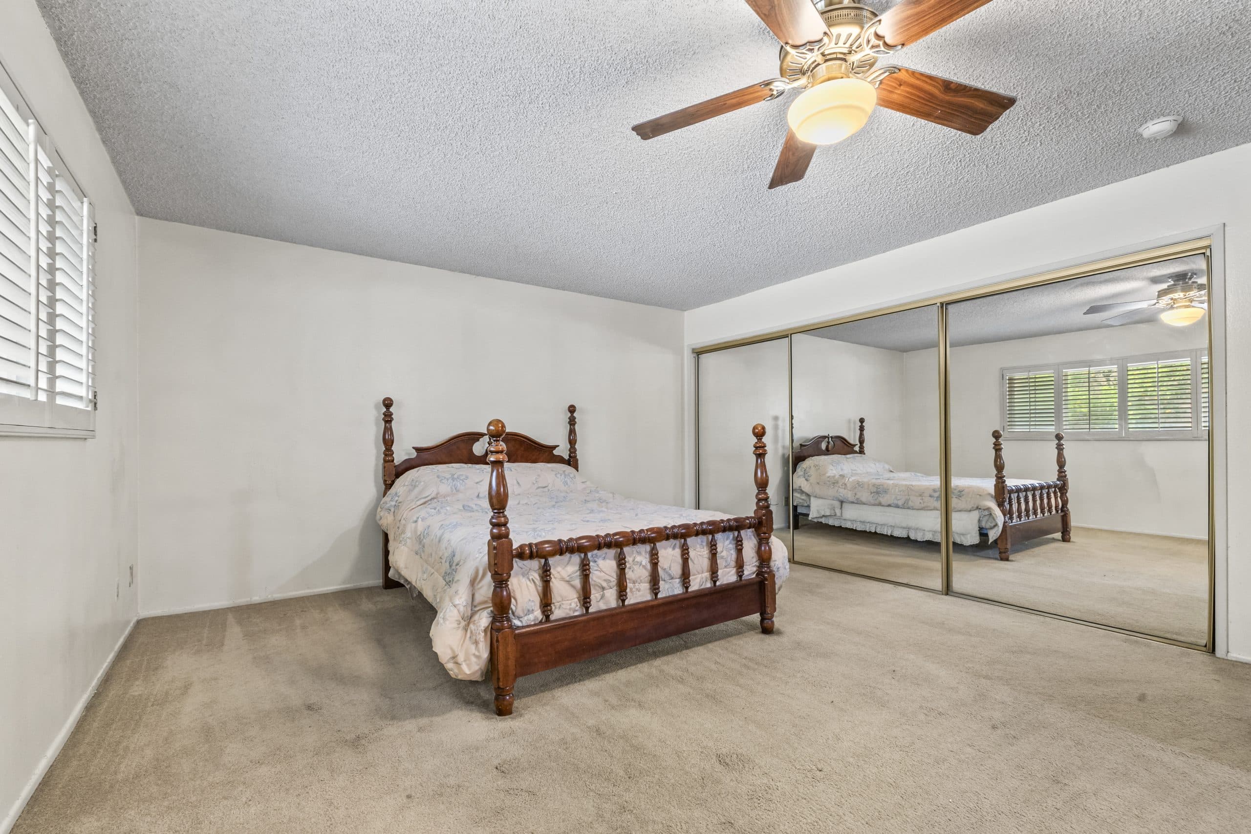 Bedroom with a four-poster bed and plantation shutters in a Claremont home