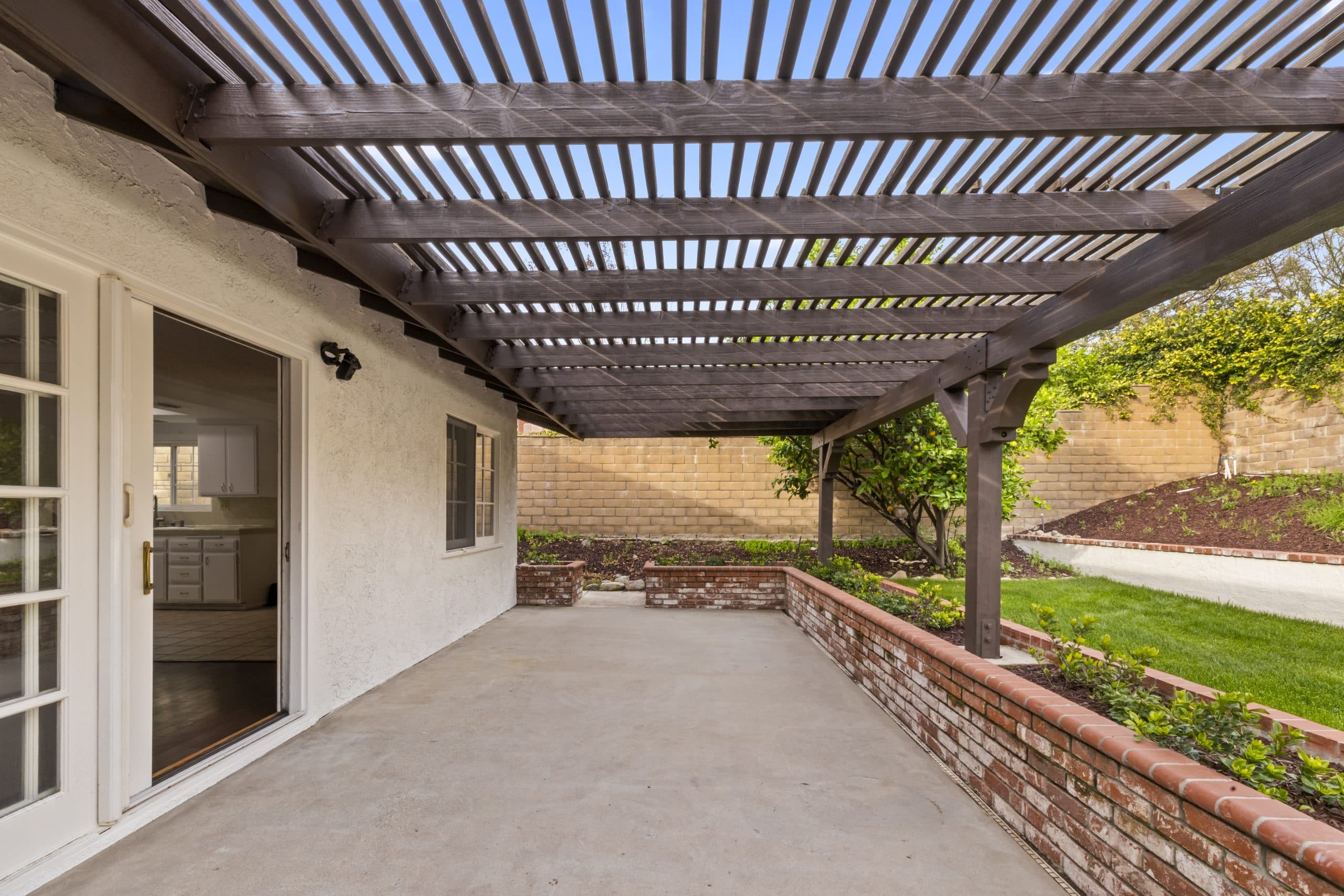 Stucco wall, used-brick planters, and a wood pergola in a Claremont courtyard