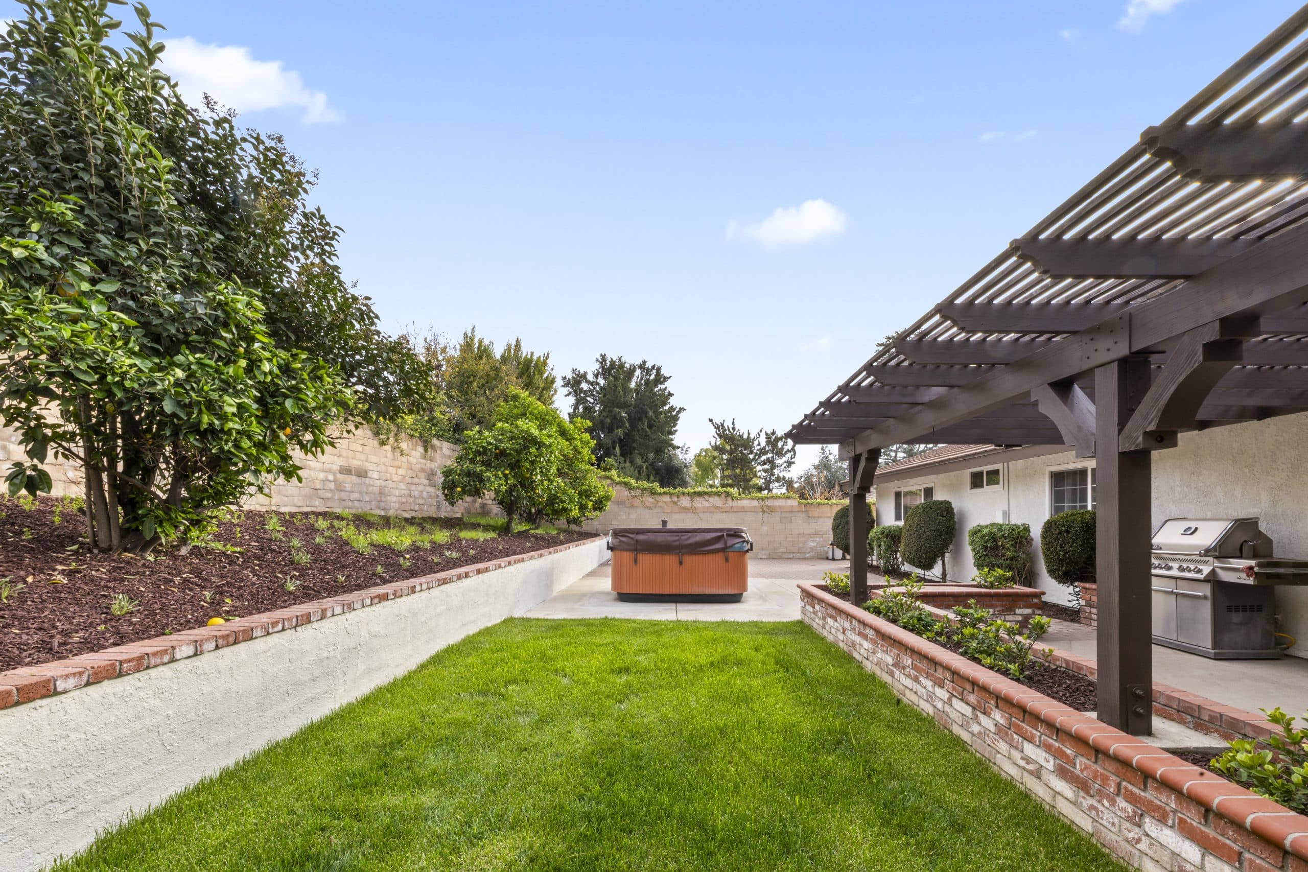 Backyard pergola with hot tub and built-in grill at a Claremont home
