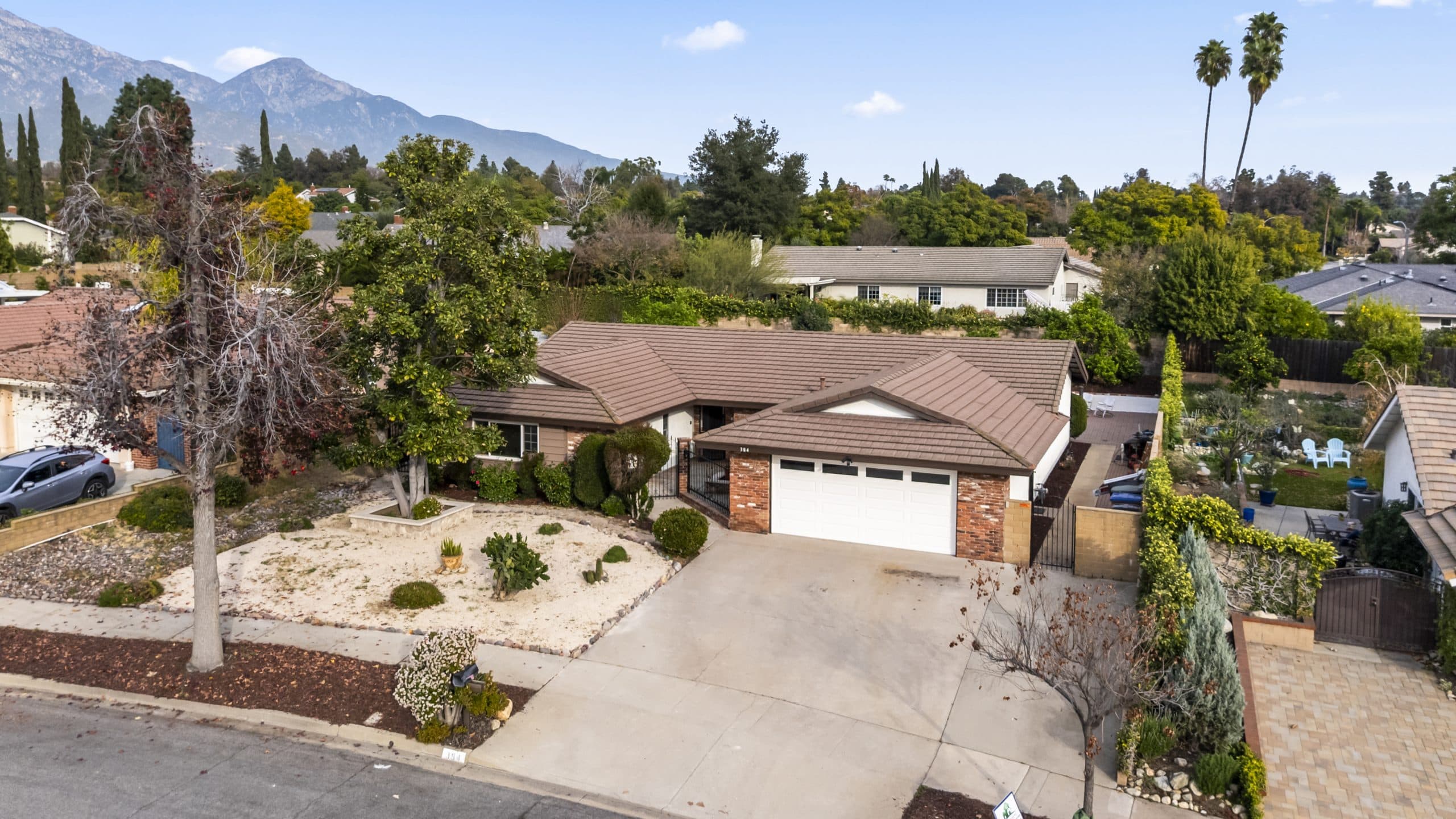 Elevated view of a tree-lined Claremont street with the San Gabriel Mountains behind
