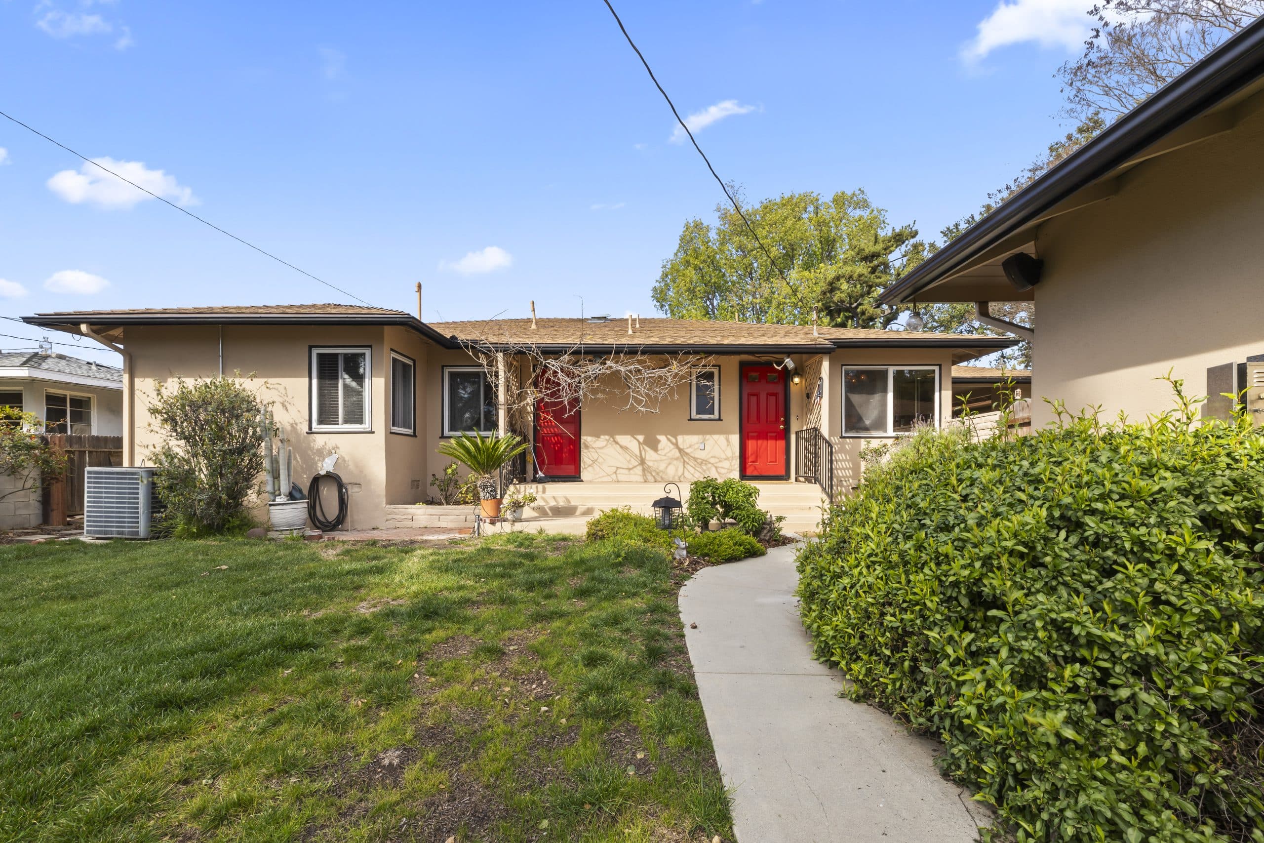 Curved front walk to the red door of a modest Claremont ranch home