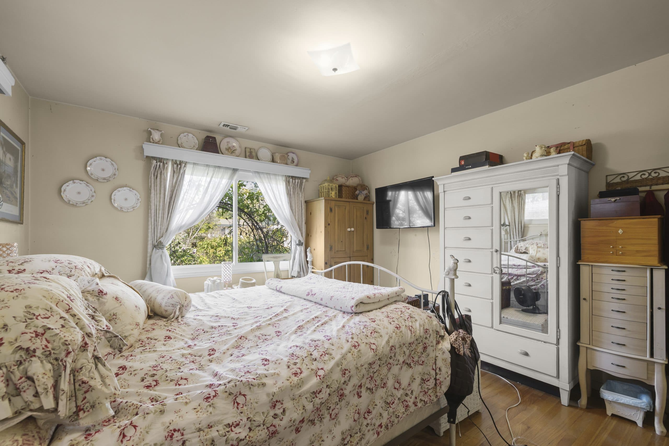 Lived-in floral bedroom in a Claremont home, still furnished the way a seller leaves it during a rent-back