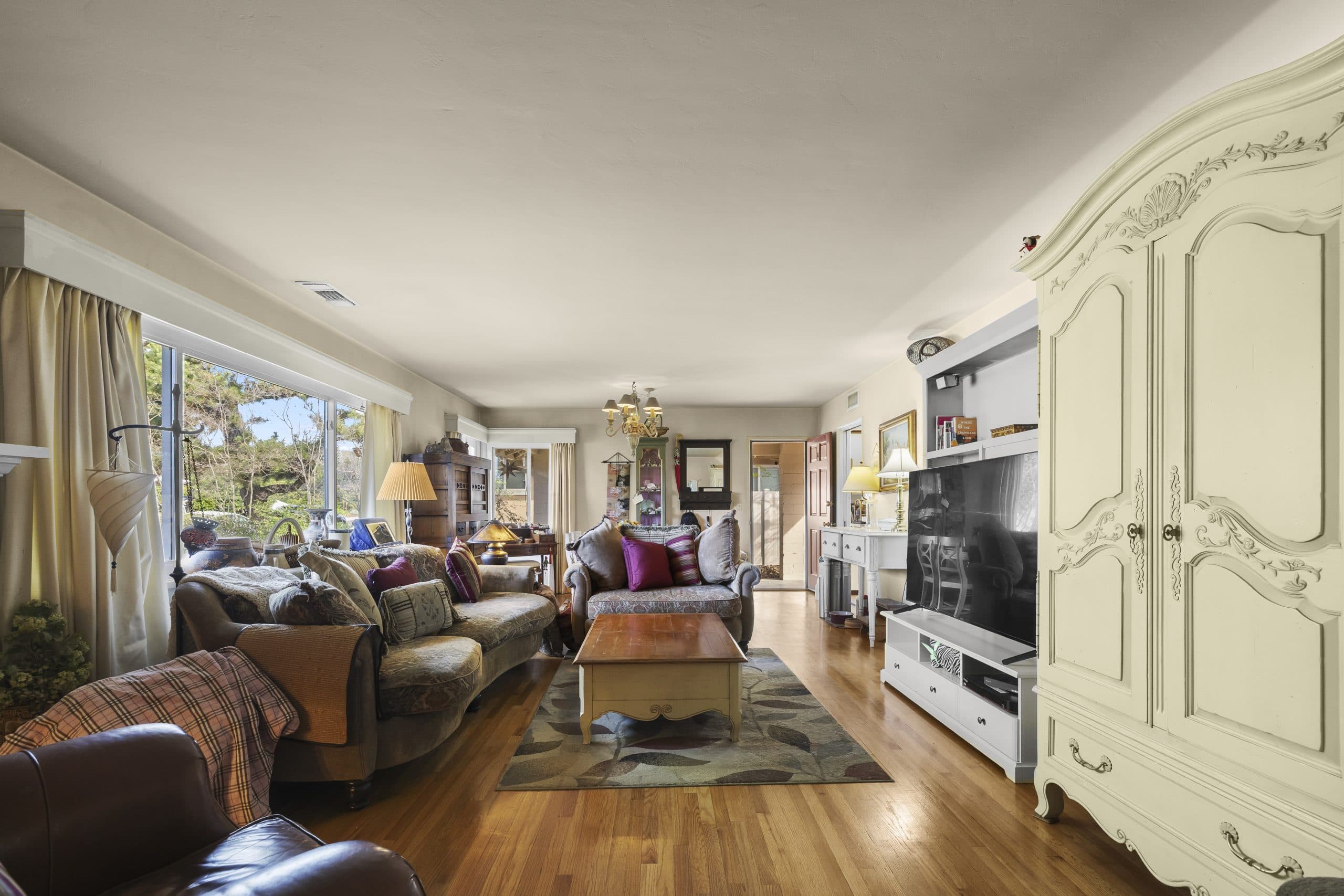 Cozy Claremont cottage living room with armoire and hardwood floors