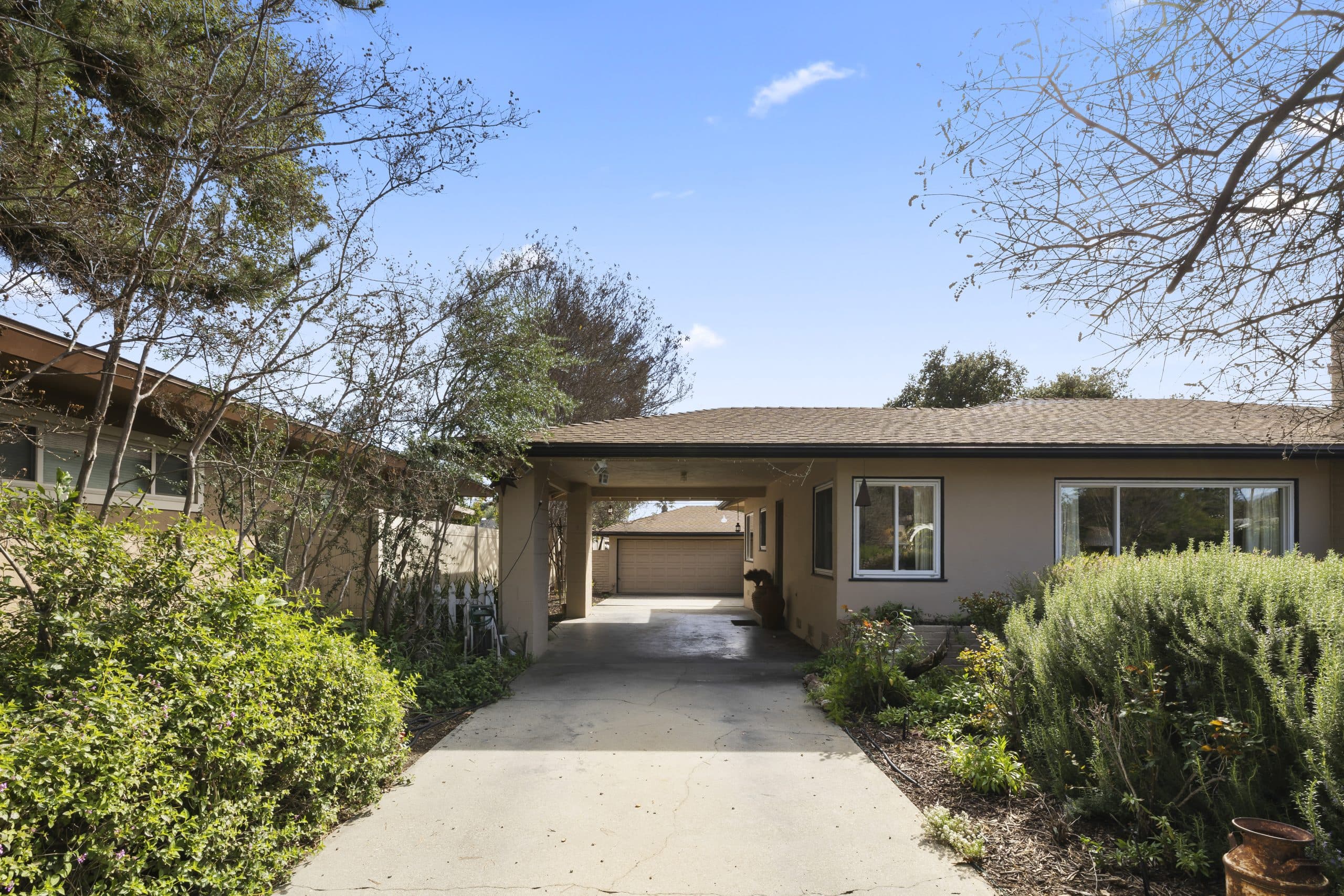 Claremont driveway passing under a covered carport toward a detached two-car garage